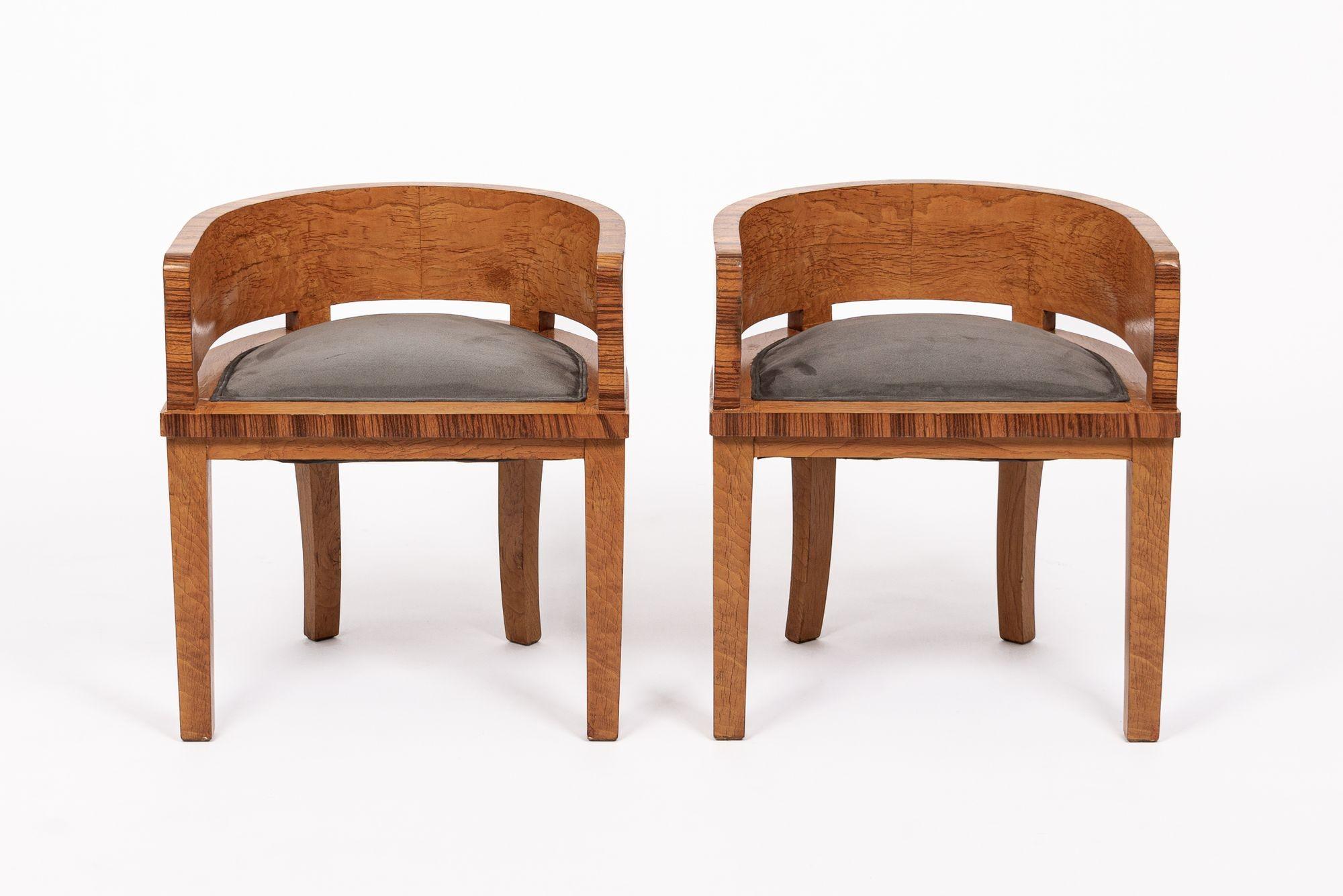 This exceptional pair of French Art Deco side armchairs or parlor chairs circa 1930 feature a unique and elegant design with a demilune (half-moon) shape. Expertly handcrafted from solid wood and rich amboyna burl wood veneer with tigerwood trim,