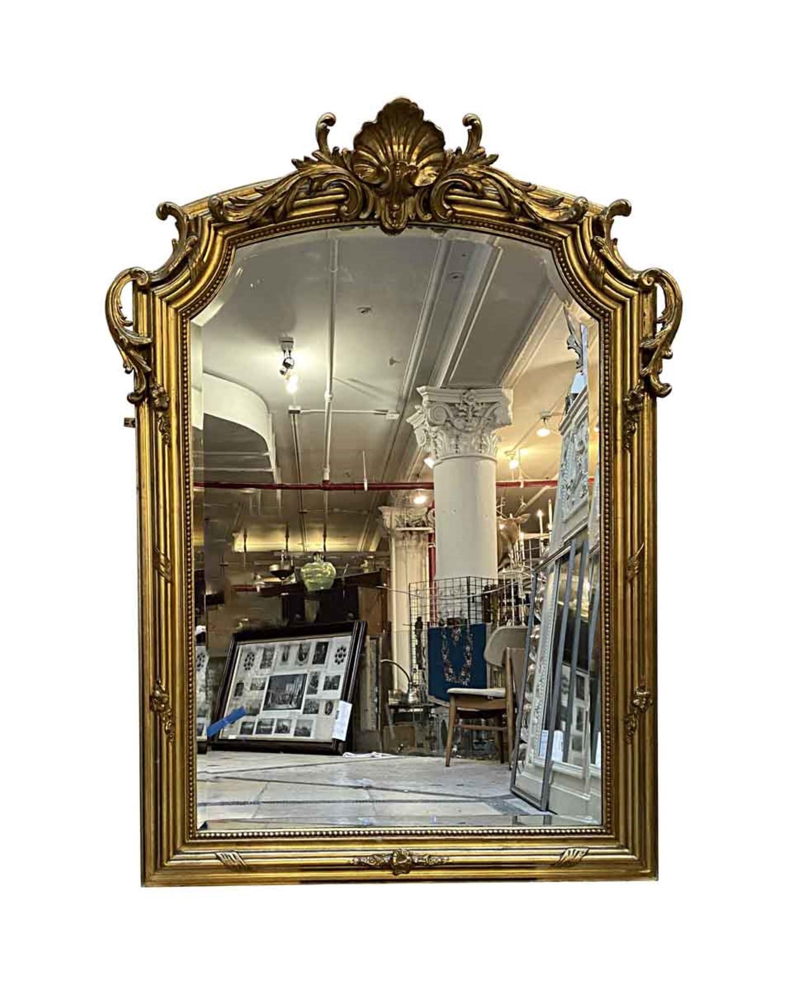 1930s antique French Rococo style hand carved wood beveled mirror with a gilded finish and ornate details. This can be seen at our 333 West 52nd St location in the Theater District West of Manhattan.