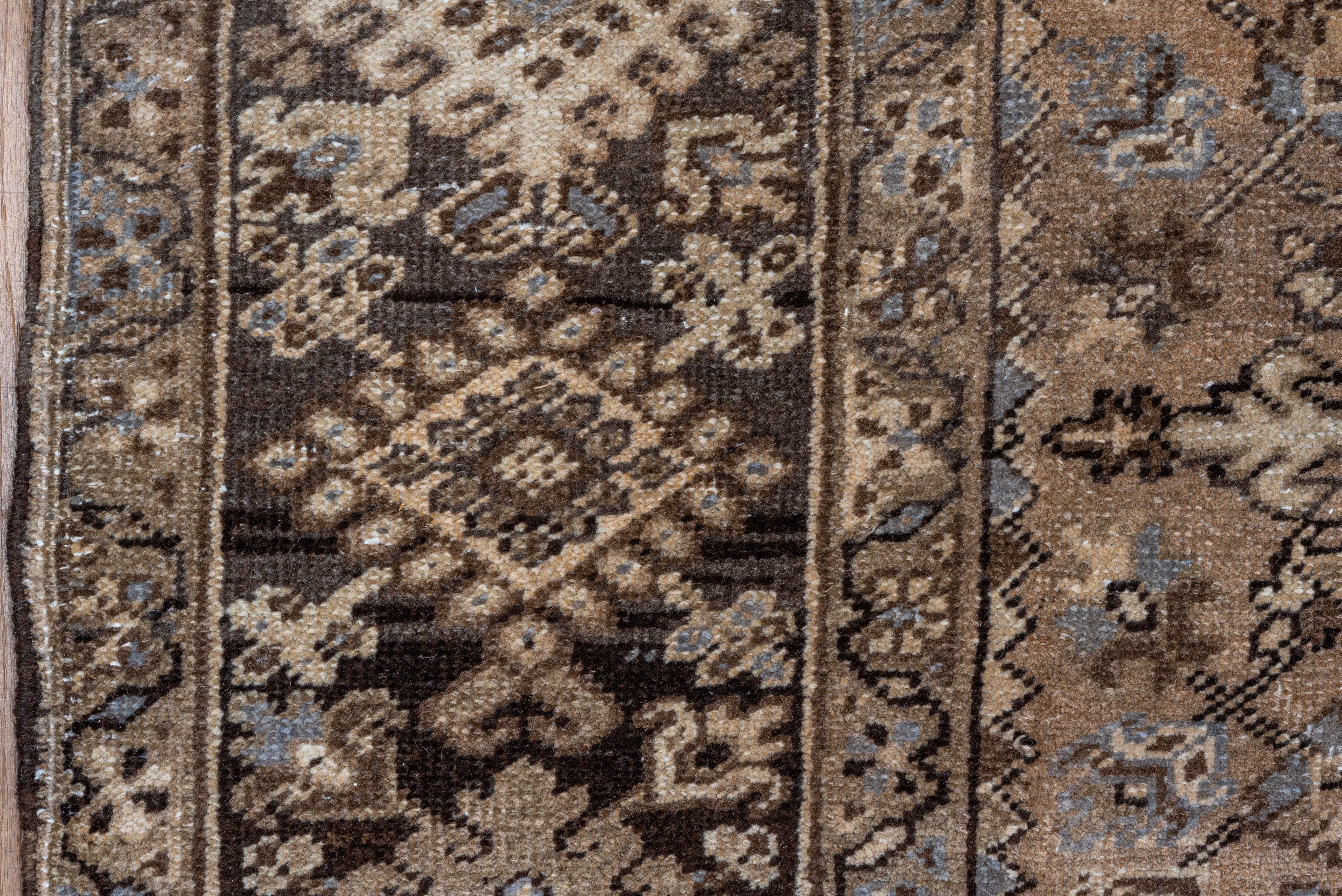This well-decorated NW Persian village carpet shows a reciprocally fringed field with a layered, en suite dark brown and ecru diamond medallion. Wide ecru conjoint corners with small floating flower décor. Dark border with chains of fringed