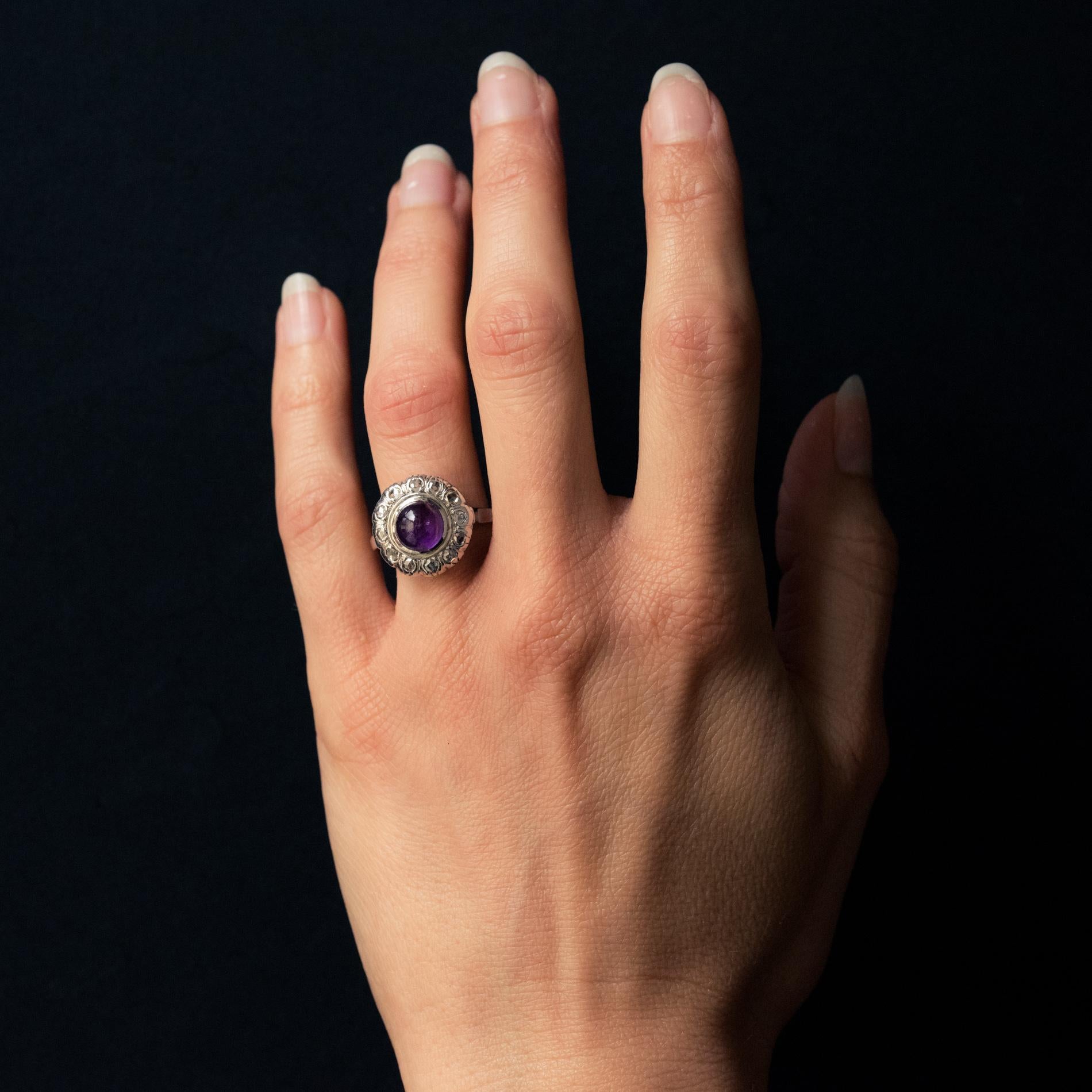 Ring aus 18 Karat Weißgold, Eulenpunze und Platin, Maskaronpunze.
Wunderschöner antiker Ring, besetzt mit einem Amethyst-Cabochon, umgeben von Diamanten im Rosenschliff auf einem gemeißelten Dekor. Der Rahmen ist filigran perforiert.
Gesamtgewicht