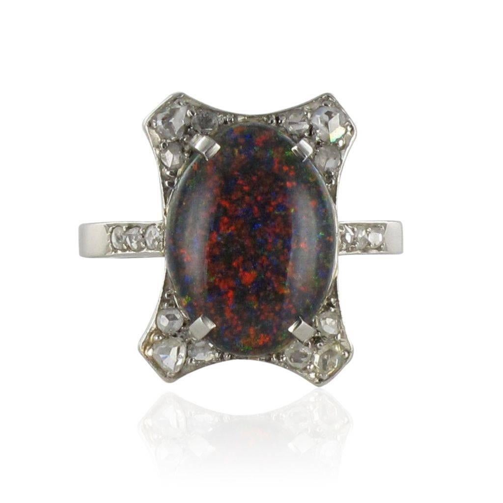 Platinum ring, grotesque hallmark.
The centrepiece of this ring is a claw set black opal accentuated by 4 x 3 rose cut claw set diamonds on an openwork bed. On each side, at the beginning of the ring band, are set 3 x 3 diamonds. 
Total weight of