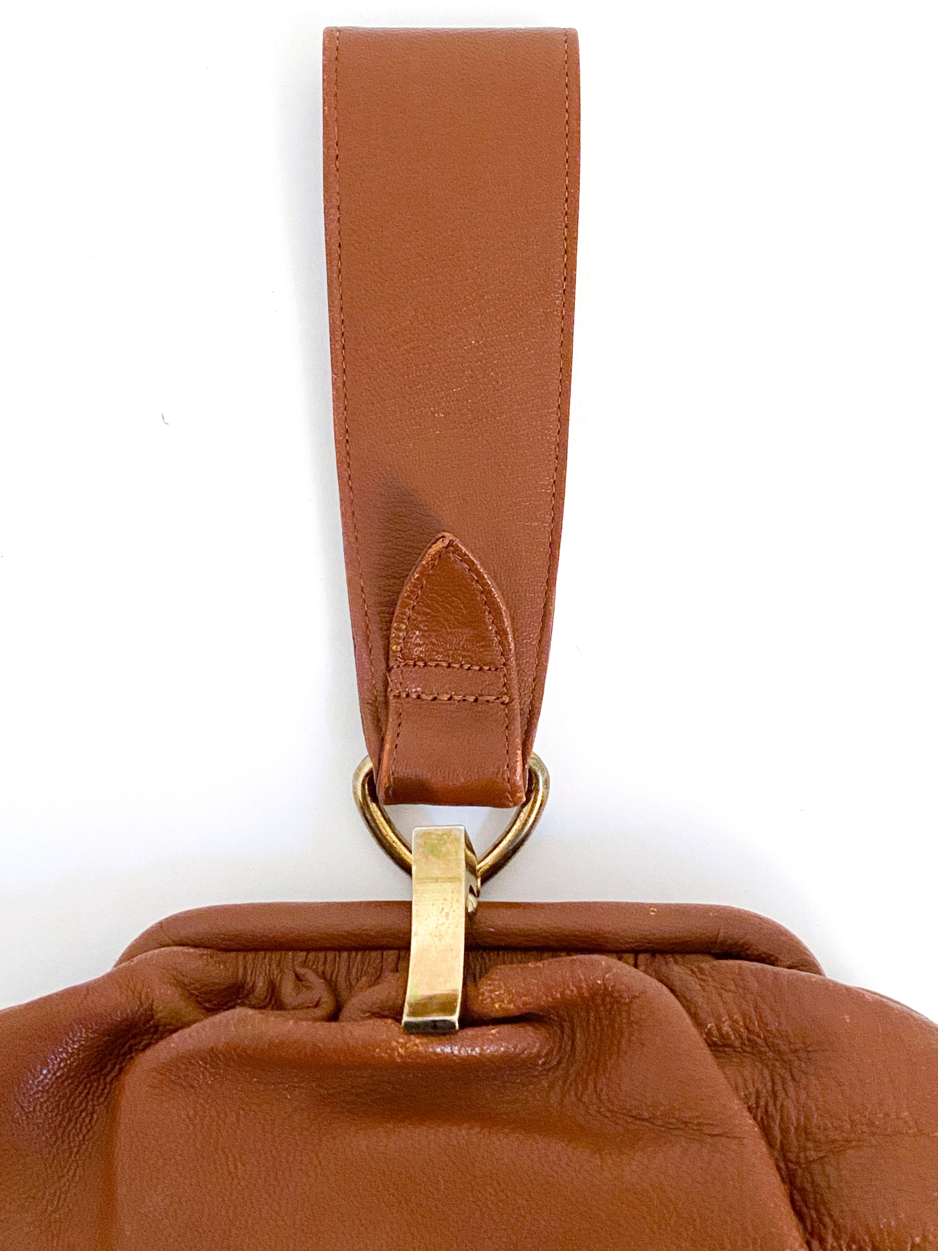 1930s Art Deco brown goat skin leather handbag with single leather wrist strap attached with brass hardware to complement the brass latch closure. The body of the bag is pleated to add volume and is semi-structured with the frame of the purse. The