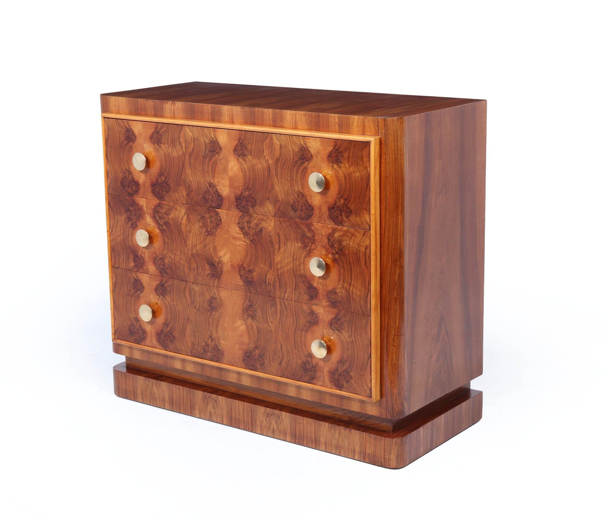 A striking and beautifully crafted Art Deco chest of drawers, dating to the 1930s. The piece is constructed in rich burr walnut with bookmatched veneers across the drawer fronts, producing a dramatic and symmetrical visual effect. The three