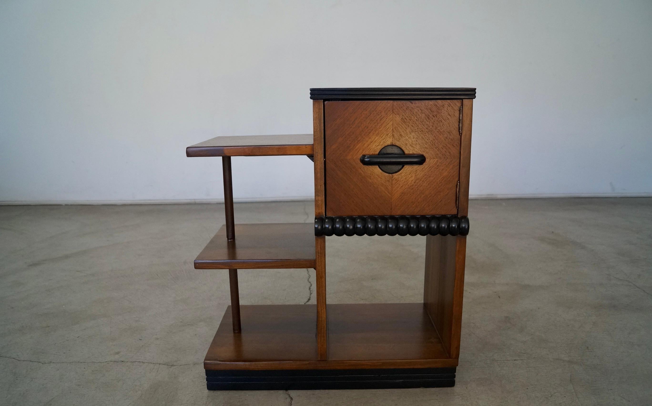 Antique Art Deco bar cabinet / shelving unit for sale. Manufactured in 1937, and stamped underneath. It has been professionally refinished, and looks beautiful. It's made of walnut, and has beautiful details on the top surfaces. It has a black base