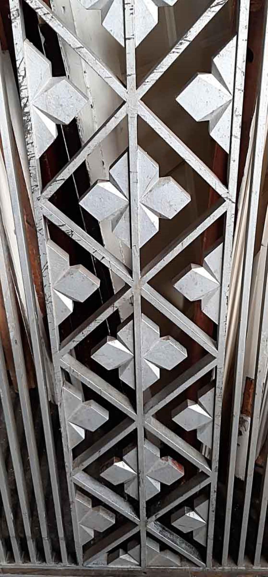 1930s Art Deco cast iron wall vent cover features a center clover pattern with vertical lines on both sides. Painted distressed silver. This can be seen at our 400 Gilligan St location in Scranton, PA.