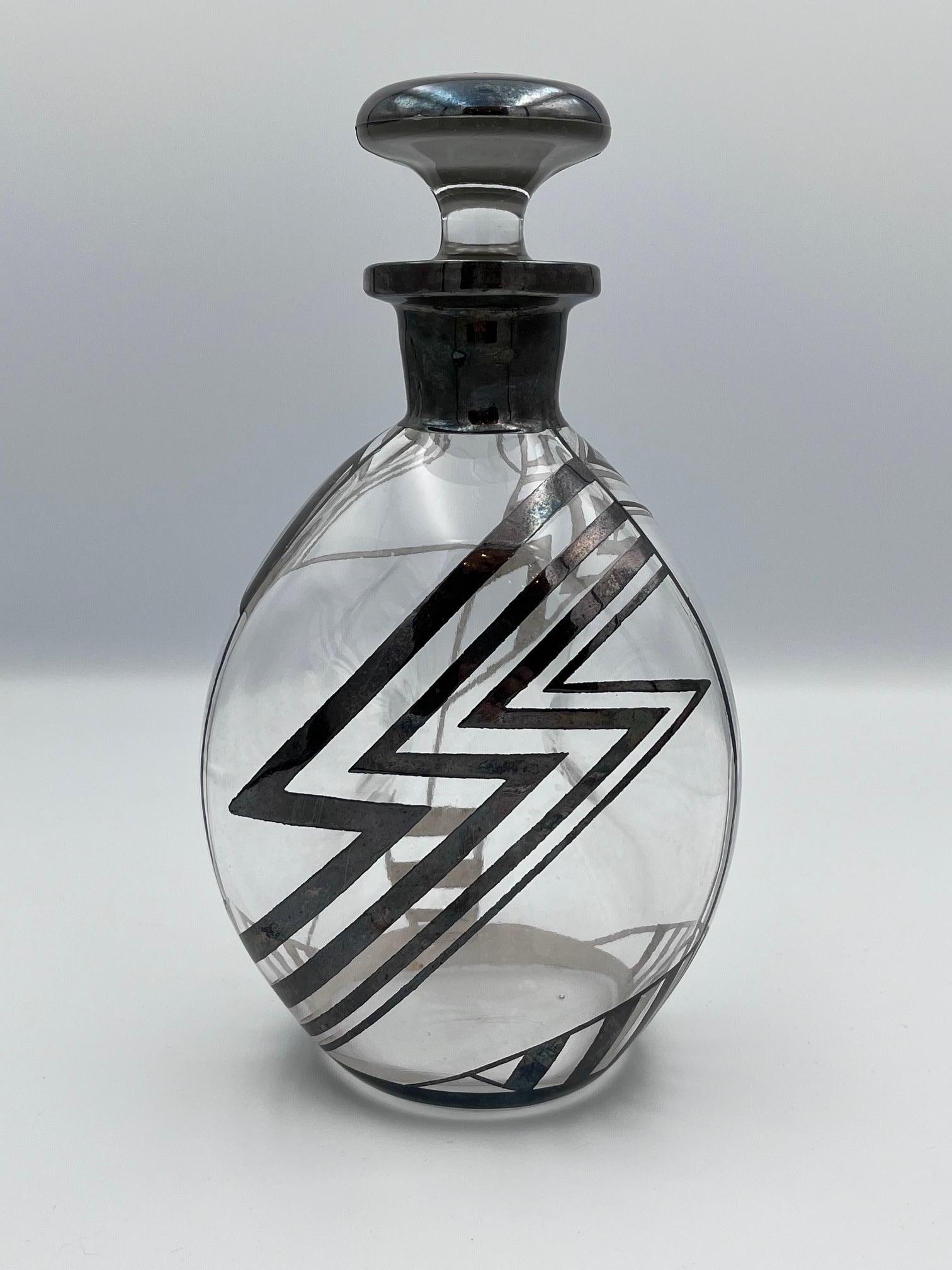 Carafe à décanter Art déco en verre et argent - motifs d'éclairs et de chevrons

Cette fabuleuse carafe Art déco est une véritable pièce d'apparat, incarnant l'énergie audacieuse et géométrique des années 1920 et 1930. Le corps en verre soufflé