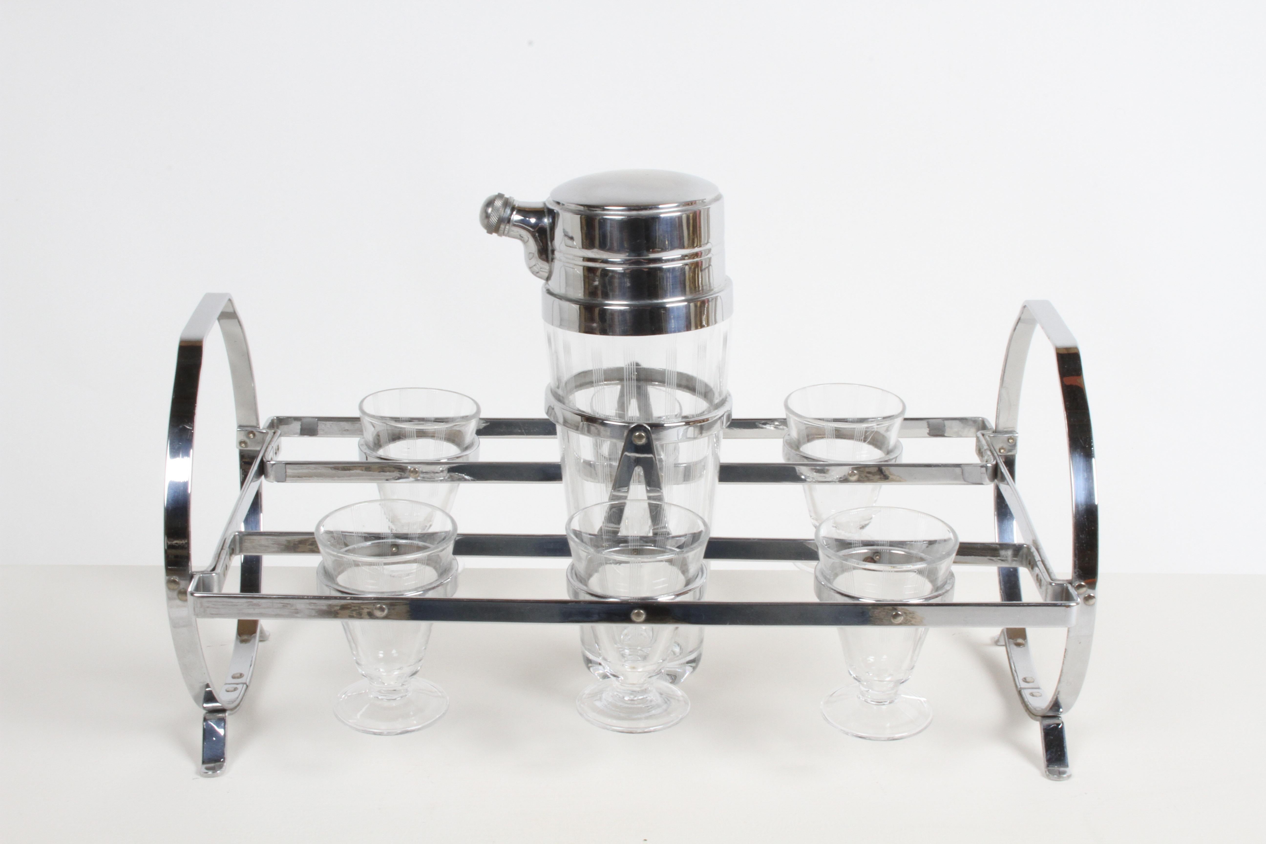 Fabulous period all original Art Deco or Machine Age Cocktail set barware set, consisting of tall etched glass cocktail shaker with chrome lid, matching etched drinking glasses on chrome Gyroscopic caddy or stand. In fine condition, with no damage