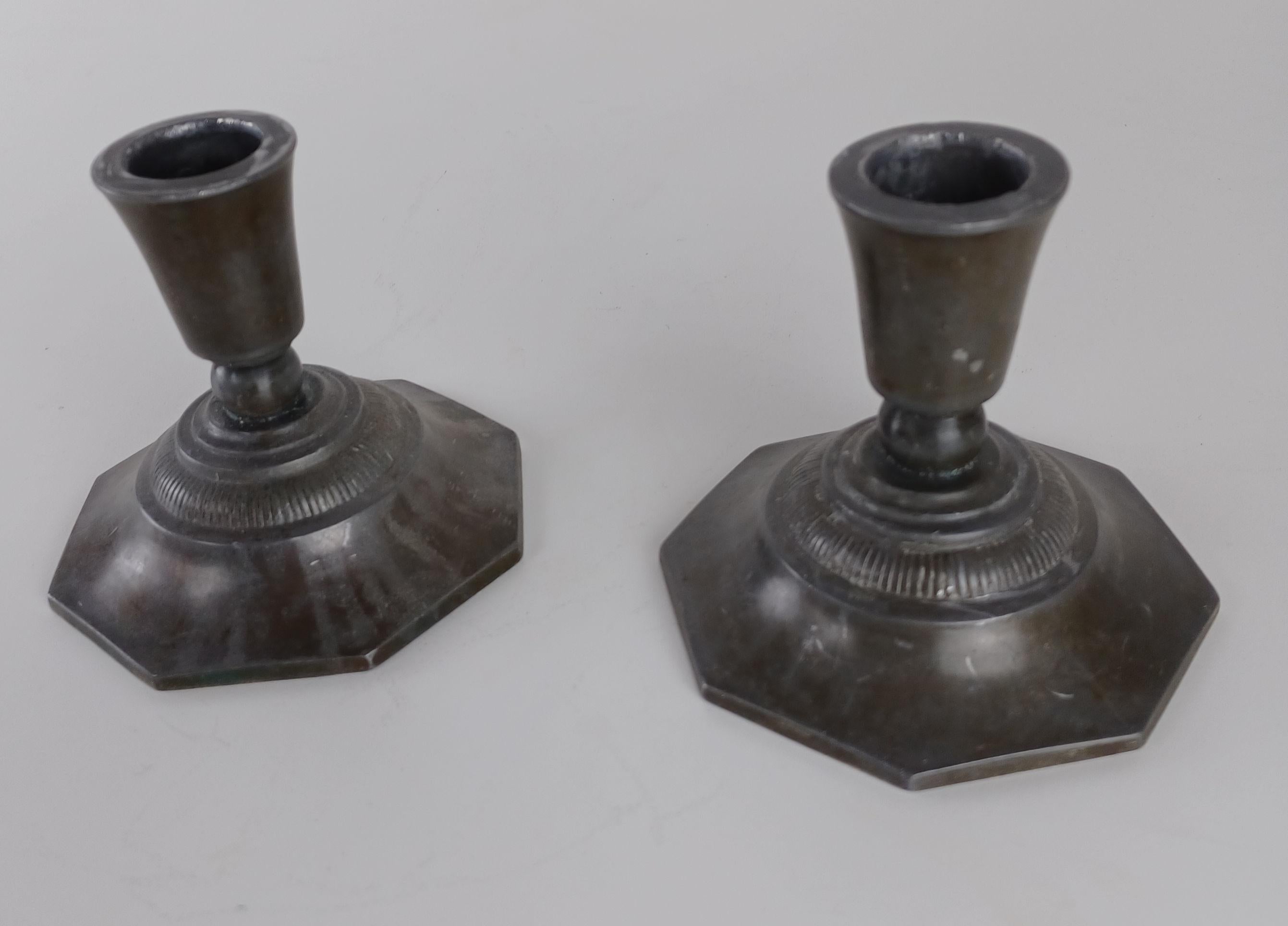1920s set of two art deco Danish Just Andersen disco metal candlesticks.

The patinated candlesticks bear witness of a long life as can be seen on the photos and are marked with Just. Andersens triangle mark. 

Just Andersen 1884-1943 was born in