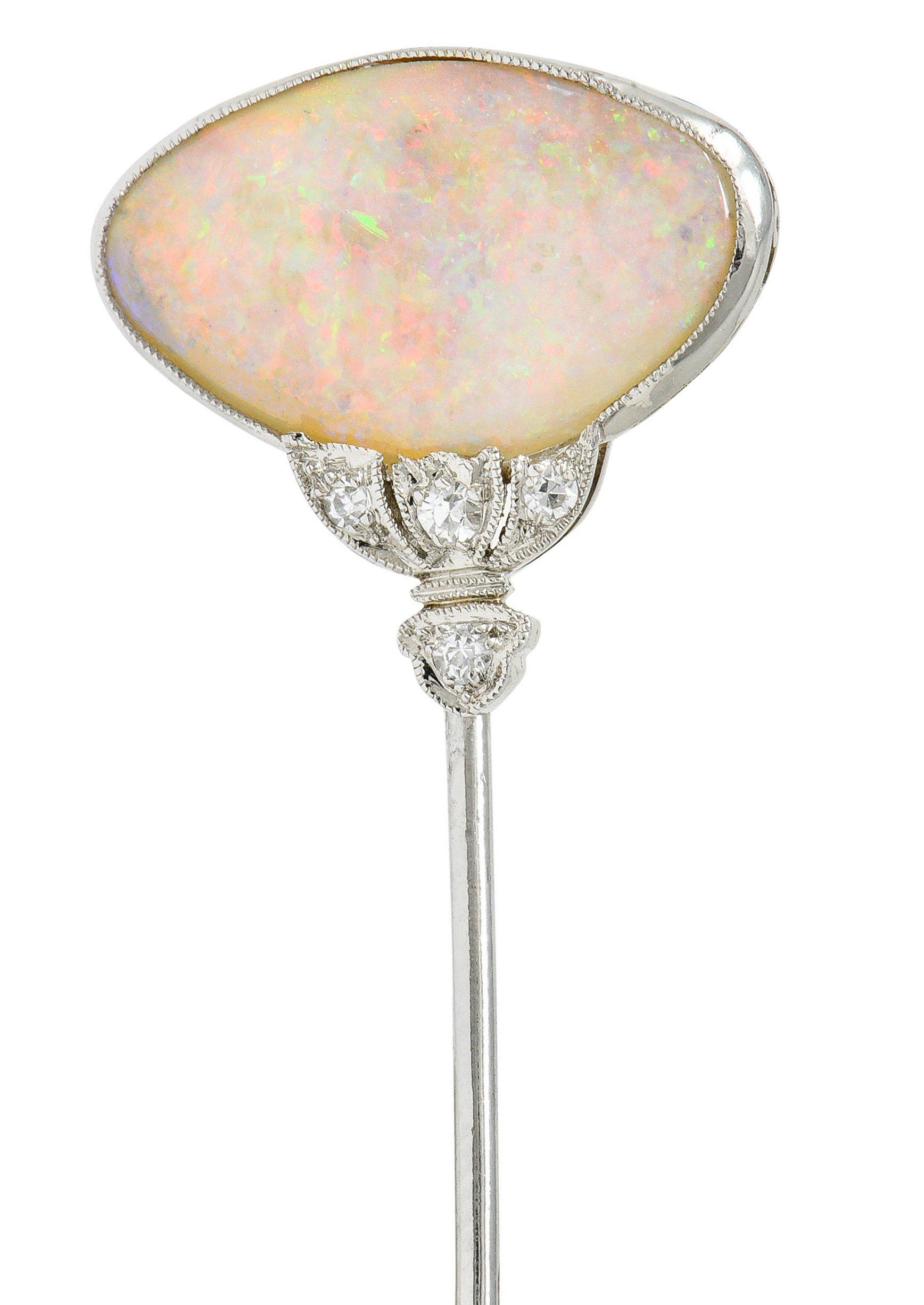 Features an elongated oval cabochon of opal measuring approximately 17.5 x 11.0 mm

Translucent white in body color with very strong spectral pinfire play-of-color

Bezel set in a milgrain surround with a stylized lotus base

Accented by single cut
