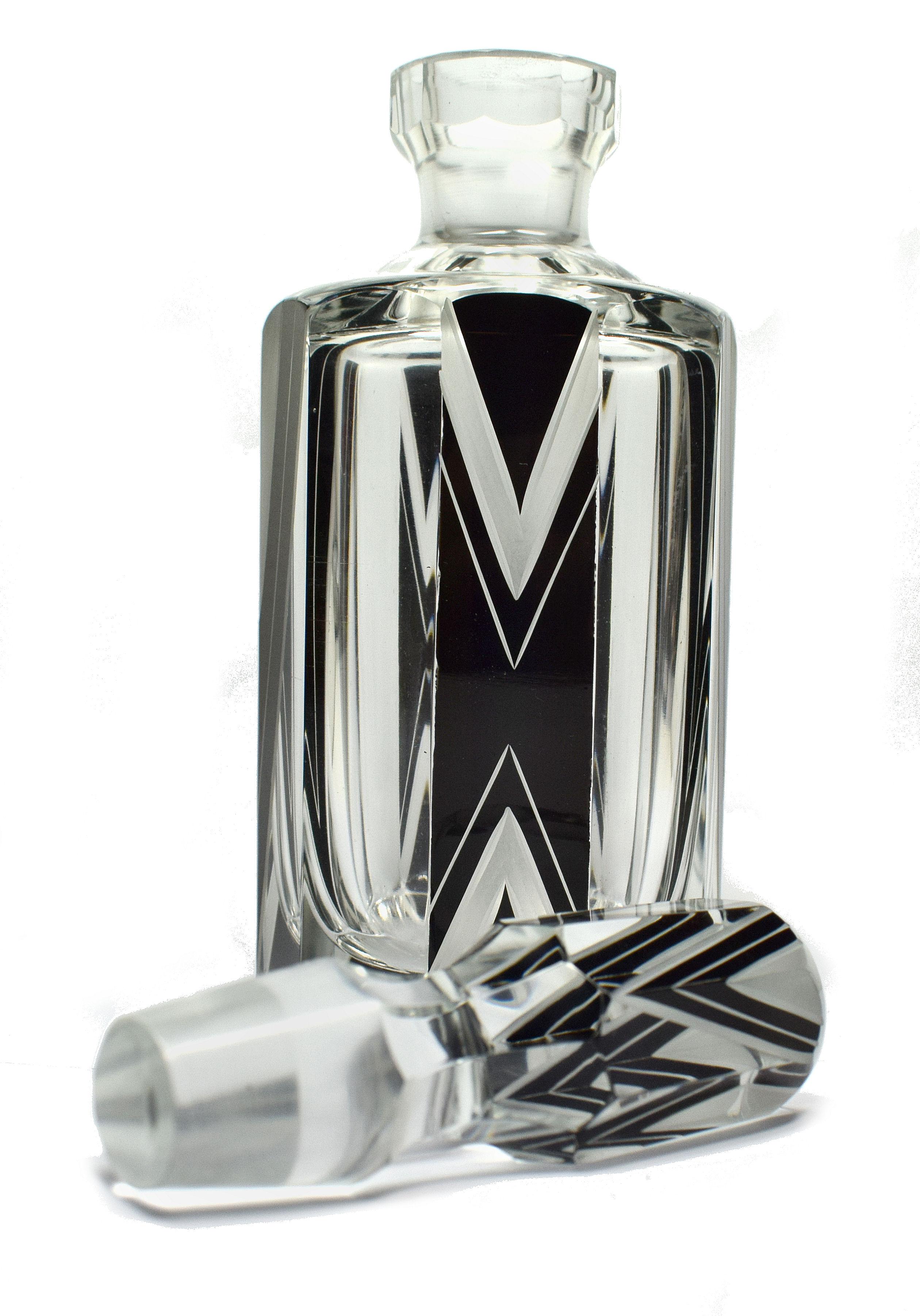 Nous vous proposons ce magnifique flacon de parfum en verre Art Déco des années 1930. Il s'agit d'une beauté absolue et d'une trouvaille rare. L'émail noir et le verre gravé de formes géométriques constituent le décor de l'extérieur de la bouteille