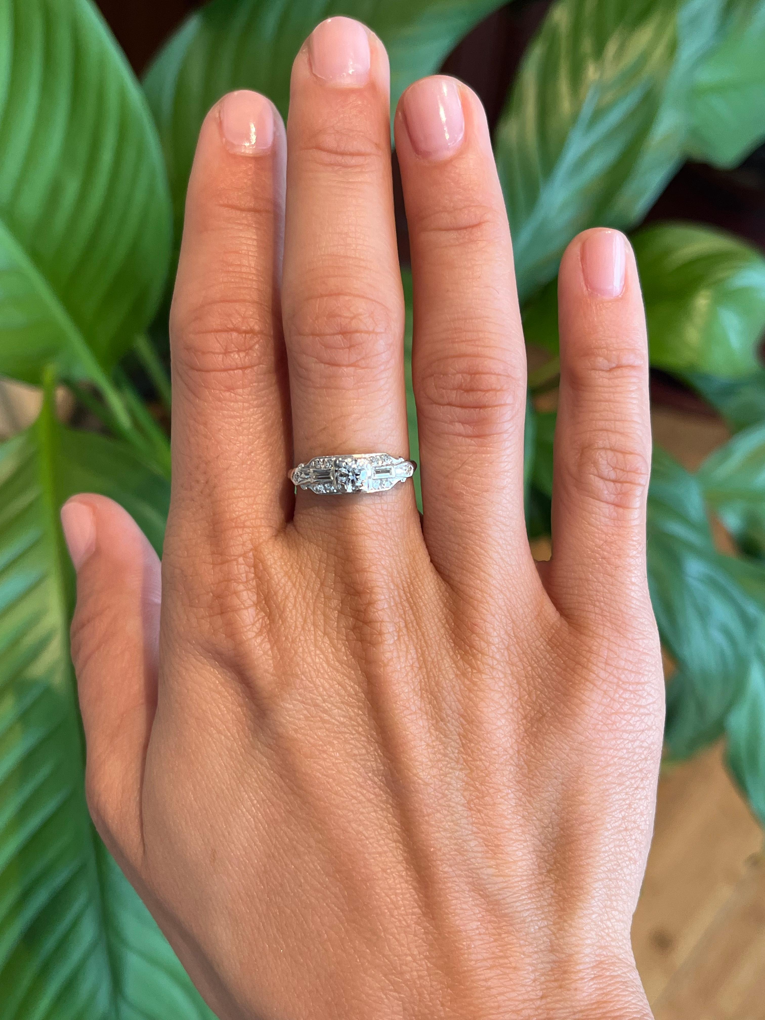 A stunning 1935 Art Deco antique engagement ring, this piece features a 0.20ct old European cut diamond with baguette and round-cut side diamonds (0.30cttw). Set in 14K white gold, this vintage ring combines geometric elegance with the brilliance of