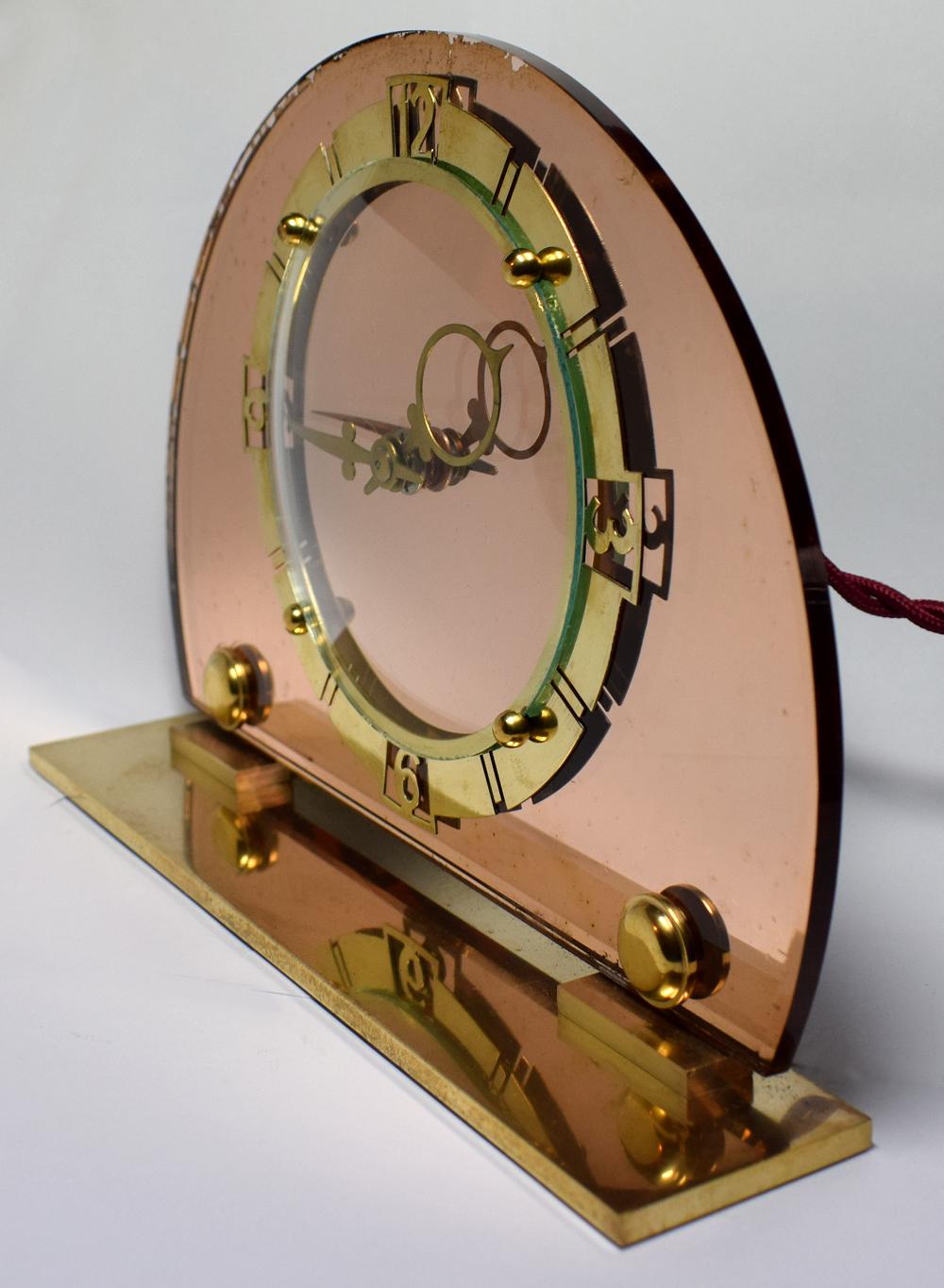 1930s Art Deco English mantel clock by the makers 'Smiths'. Half moon peach mirror glass with fretted out brass numerals contrast beautifully. Runs on electric so no winding needed and is in good working order. There is some age related foxing to