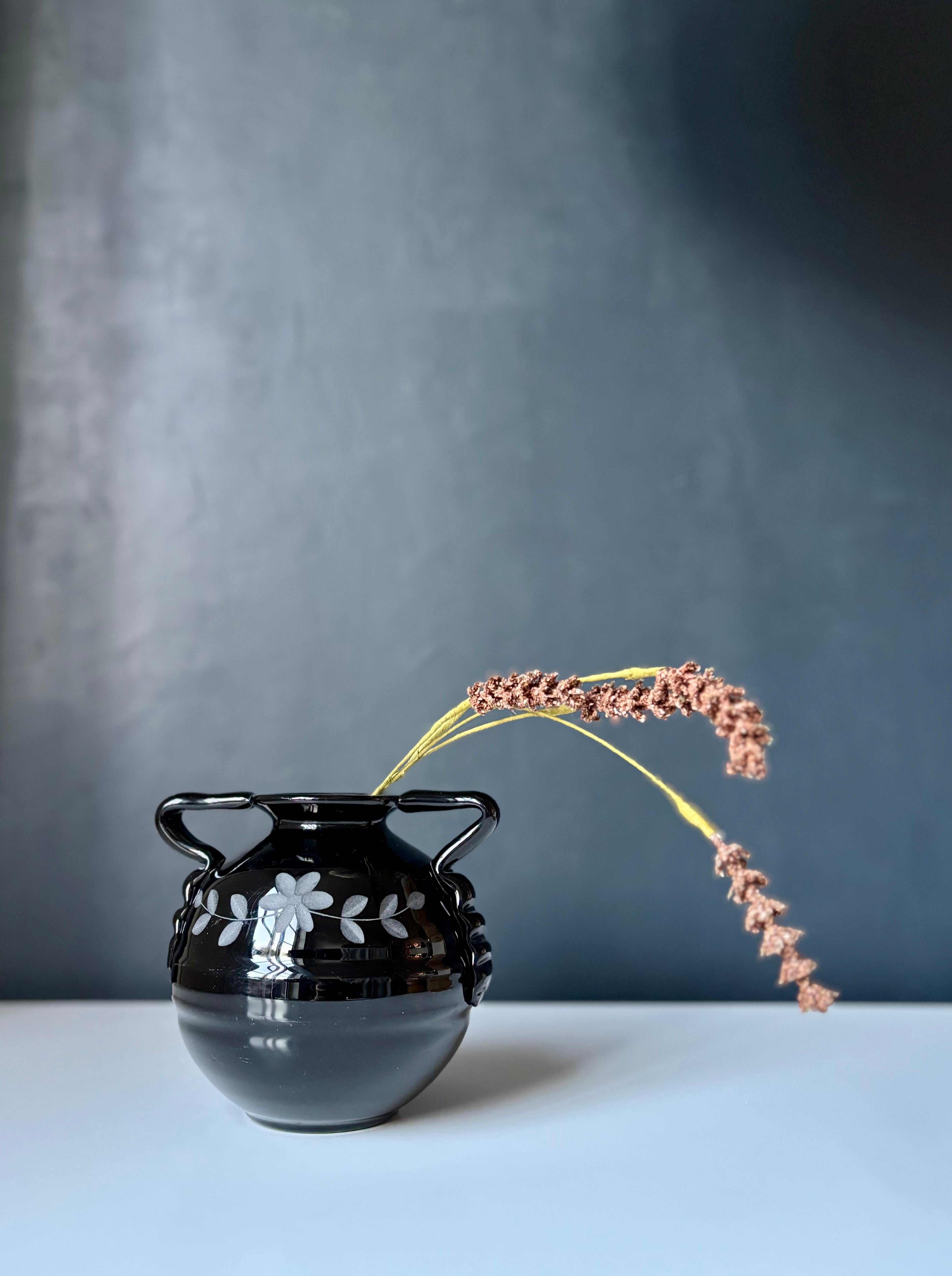 Vaso a sfera in vetro Art Deco soffiato a bocca di colore nero lucido attribuito alla ditta svedese Emmaboda Glasbruk, circa 1930. Manici decorativi ondulati e incisioni floreali stilizzate e smerigliate sulla parte anteriore e posteriore.