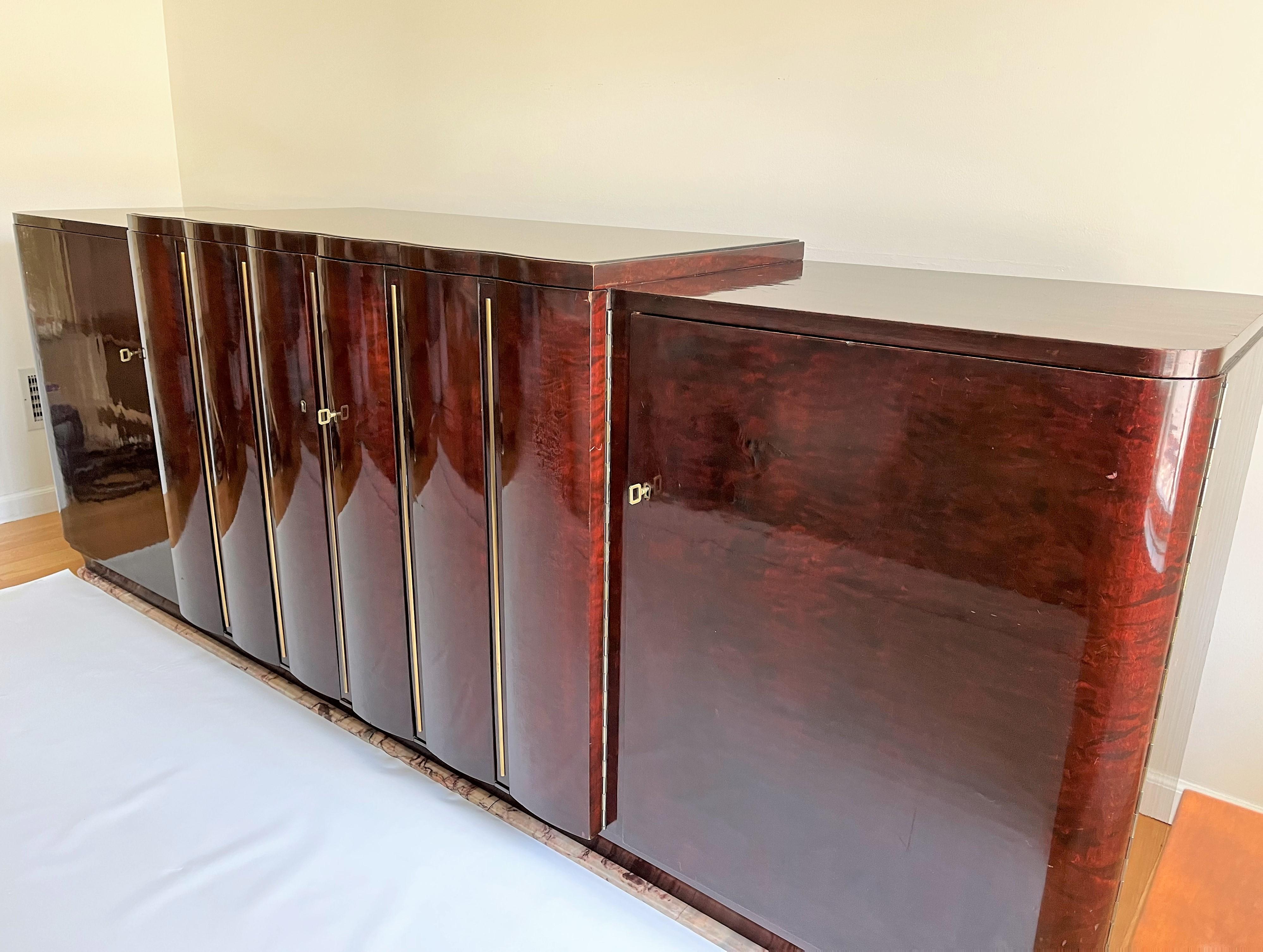 Exceptional Art Deco sideboard, flamed-rosewood veneer, in the middle 4 drawers, 3 shelves, 2 scalloped doors with brass vertical design and smoked mirrored scalloped top, on both sides curved doors, 3 shelves and flamed-rosewood veneered top,