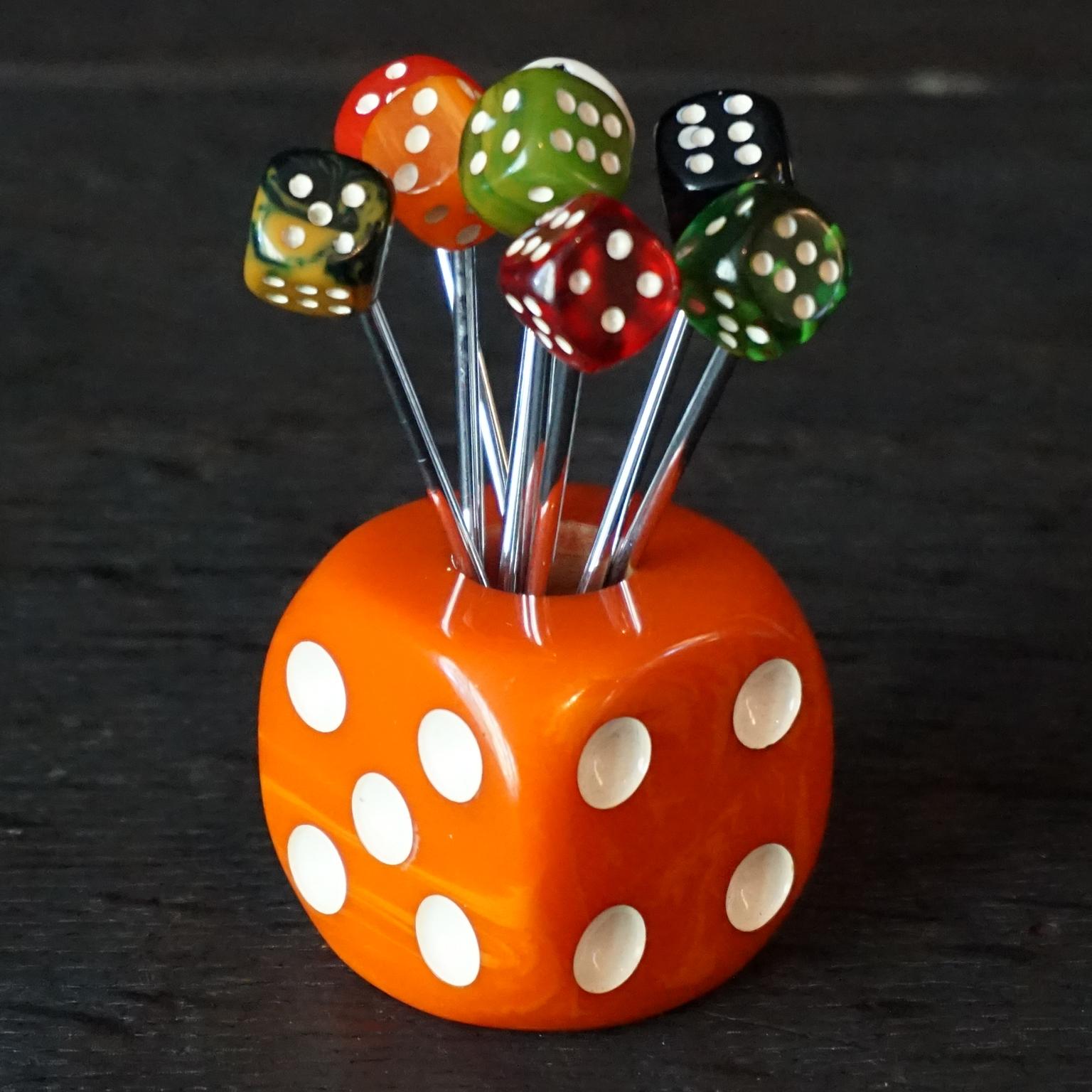 What a lovely collector's item this orange French 1930s Art Deco bakelite cocktail pick holder with 8 cocktail picks is.
Each pick has its own bakelite dice in a different colour, so it will be easy to remember which one is yours.

Eat your