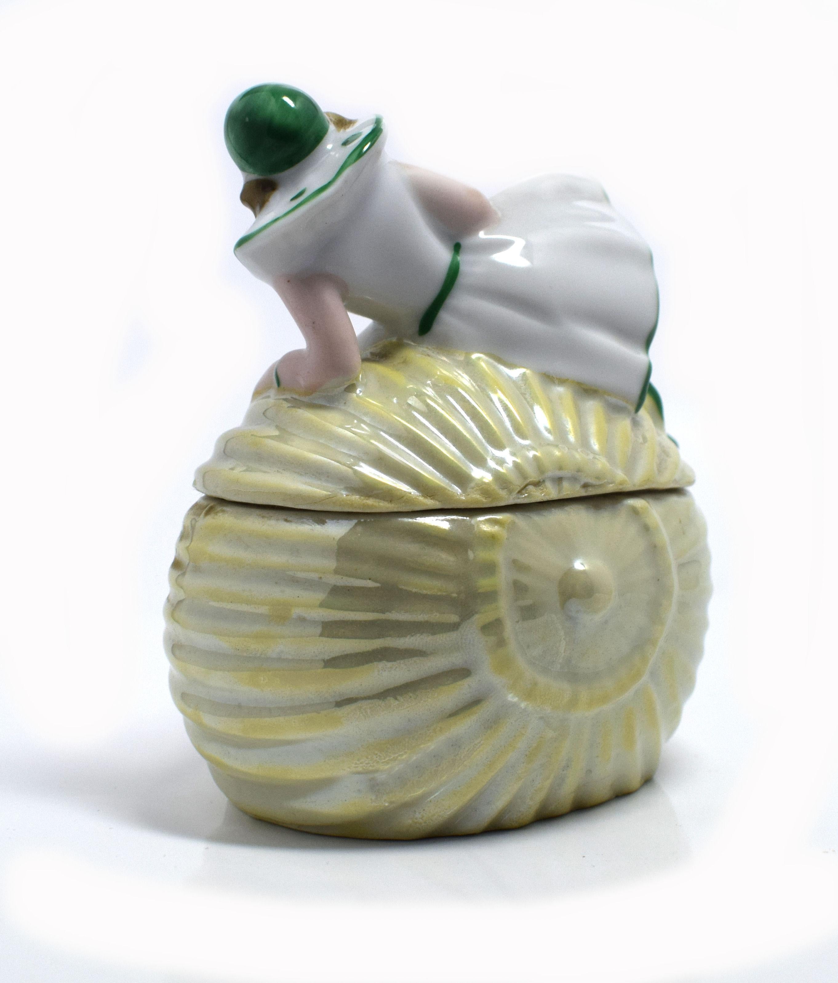 For your consideration is this delightful early 1930s Art Deco porcelain Souvenir beach powder jar /box. Depicting a reclining Pierrot on a conch shell and originating from France. Beautifully hand painted with pearled finish to the shell. She once