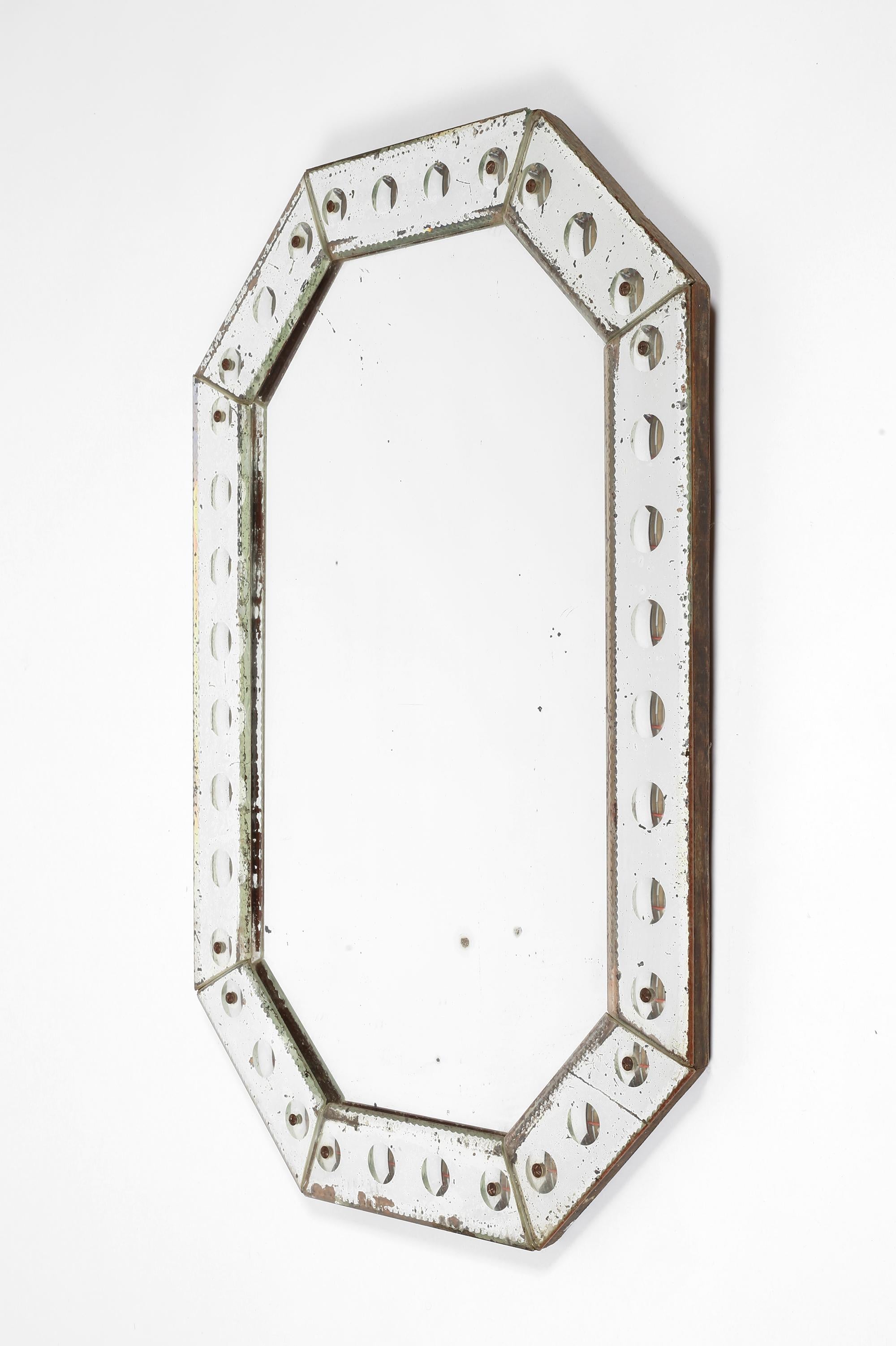 Un rare et magnifique miroir octogonal vénitien renardé de la période Art Déco. La bordure est décorée de rondeaux atypiques et simples sur toute sa longueur. 