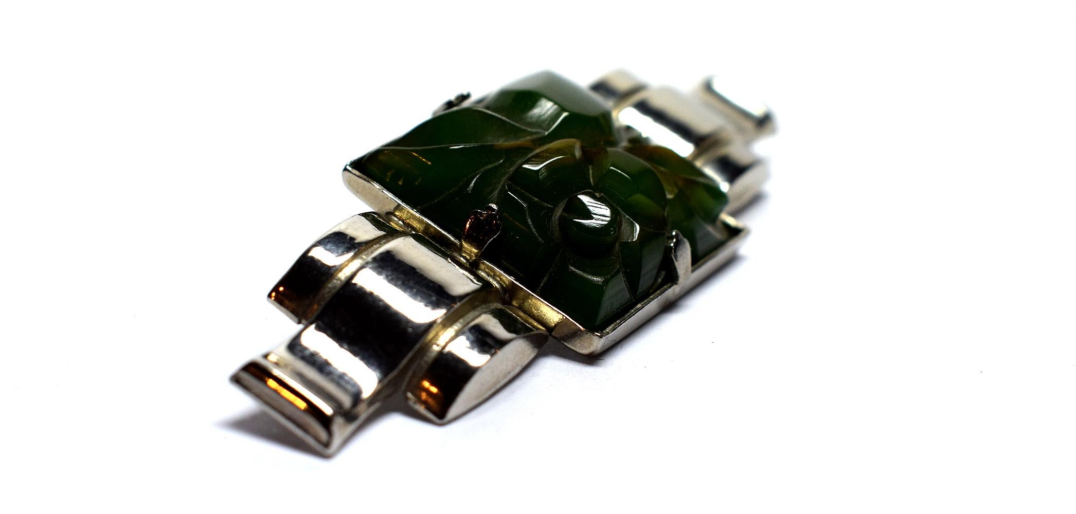 Very attractive ladies Art Deco brooch, totally authentic and to the period, dating to the 1930s. Features an emerald green phenolic Bakelite carved floral center piece which is mounted on a chrome serpentine back plate. The whole brooch is in