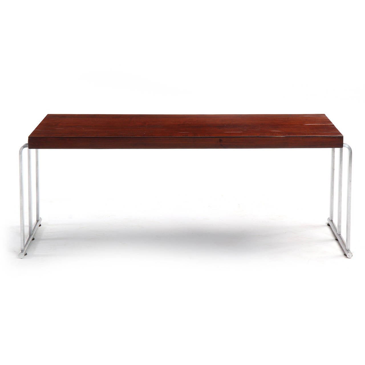 A low table or bench with a rectangular mahogany top floating a bent chromed steel base with sled feet.