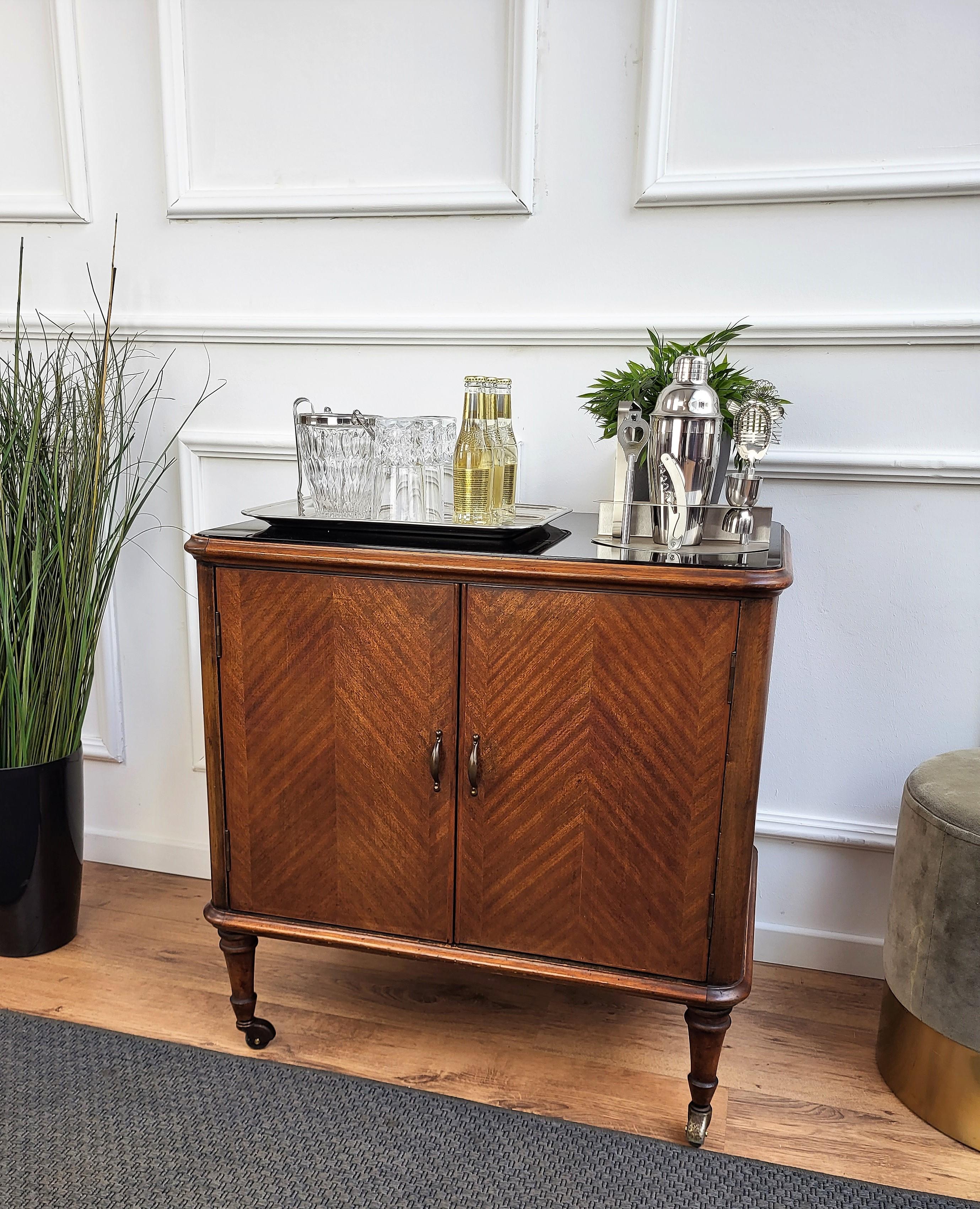 Unique and very elegant Italian Art Deco Mid-Century dry bar cabinet cart, in walnut wood with black glass top, double front door and when opened having amazing interior part in mirror mosaic. The piece is highlighted by the original antique brass