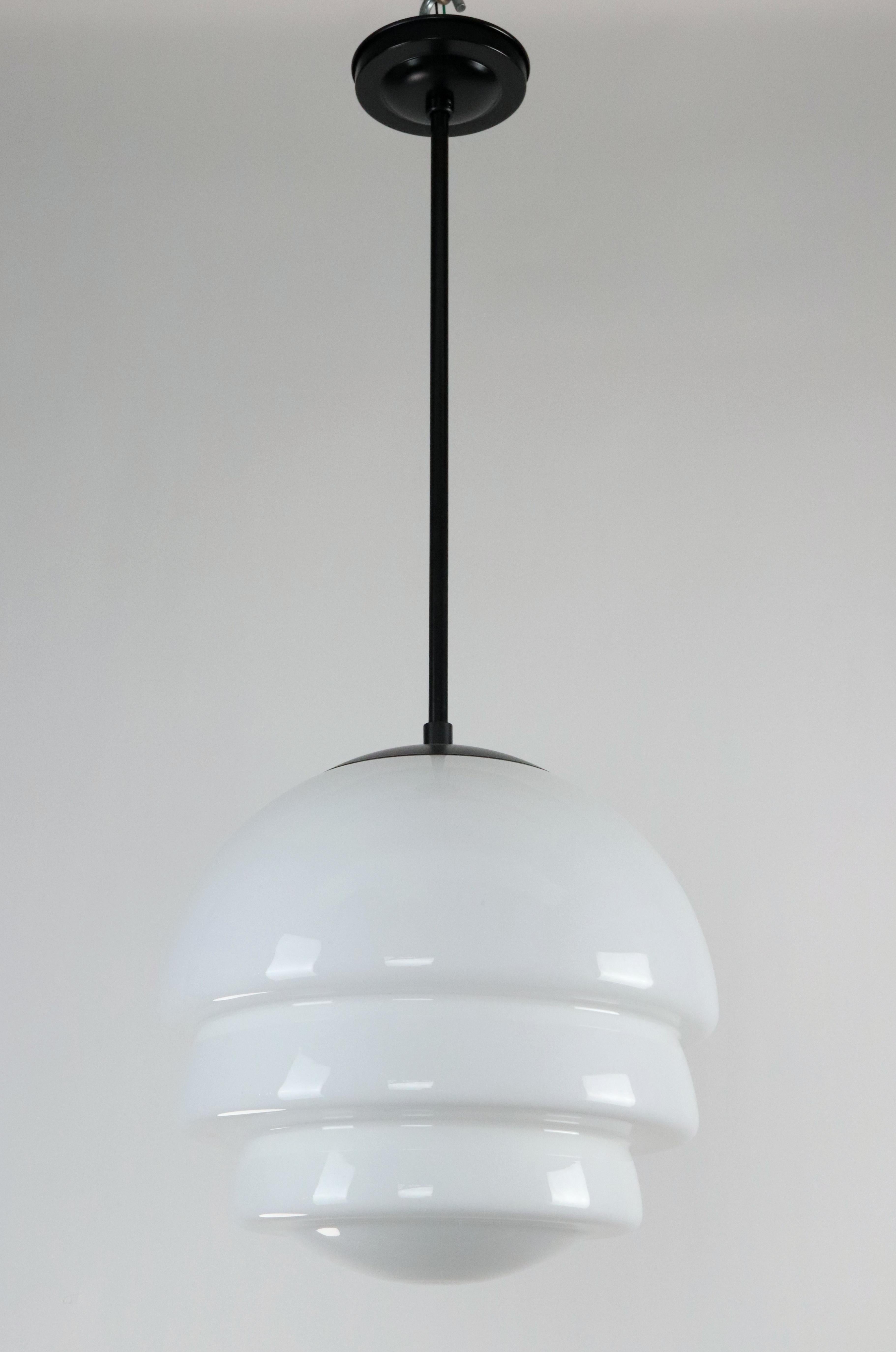 Art Deco style pendant light with a three tier stacked dome shaped white milk glass globe and black finished steel pole. Cleaned and restored. This light requires one Edison style medium base light bulb. This light is cleaned, wired, and ready to
