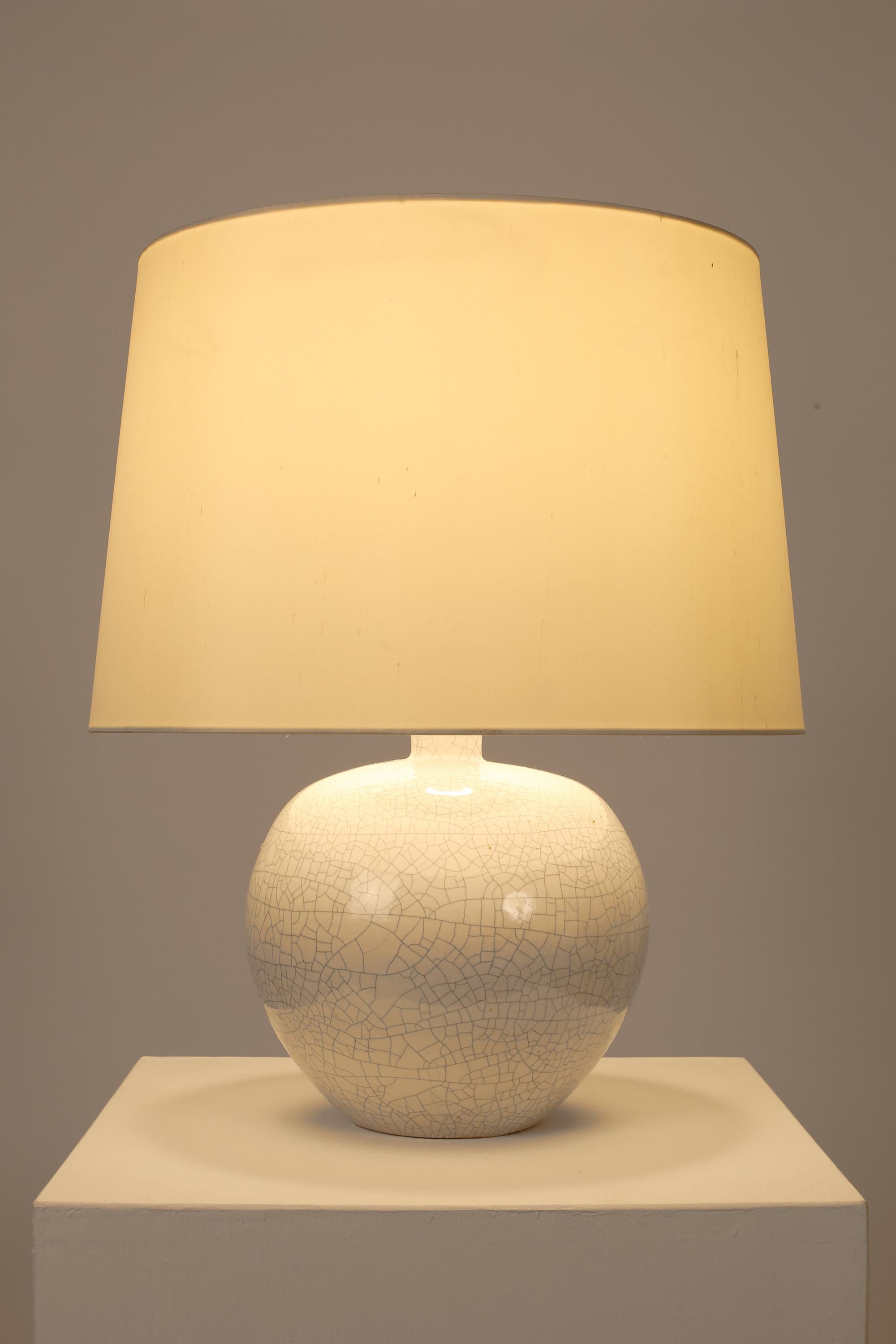 Lampe de table Art Déco en céramique émaillée blanc cassé, de forme trapue et semblable à une bouteille. Français, c. C. C. Livré avec un abat-jour en soie dupion blanc cassé.