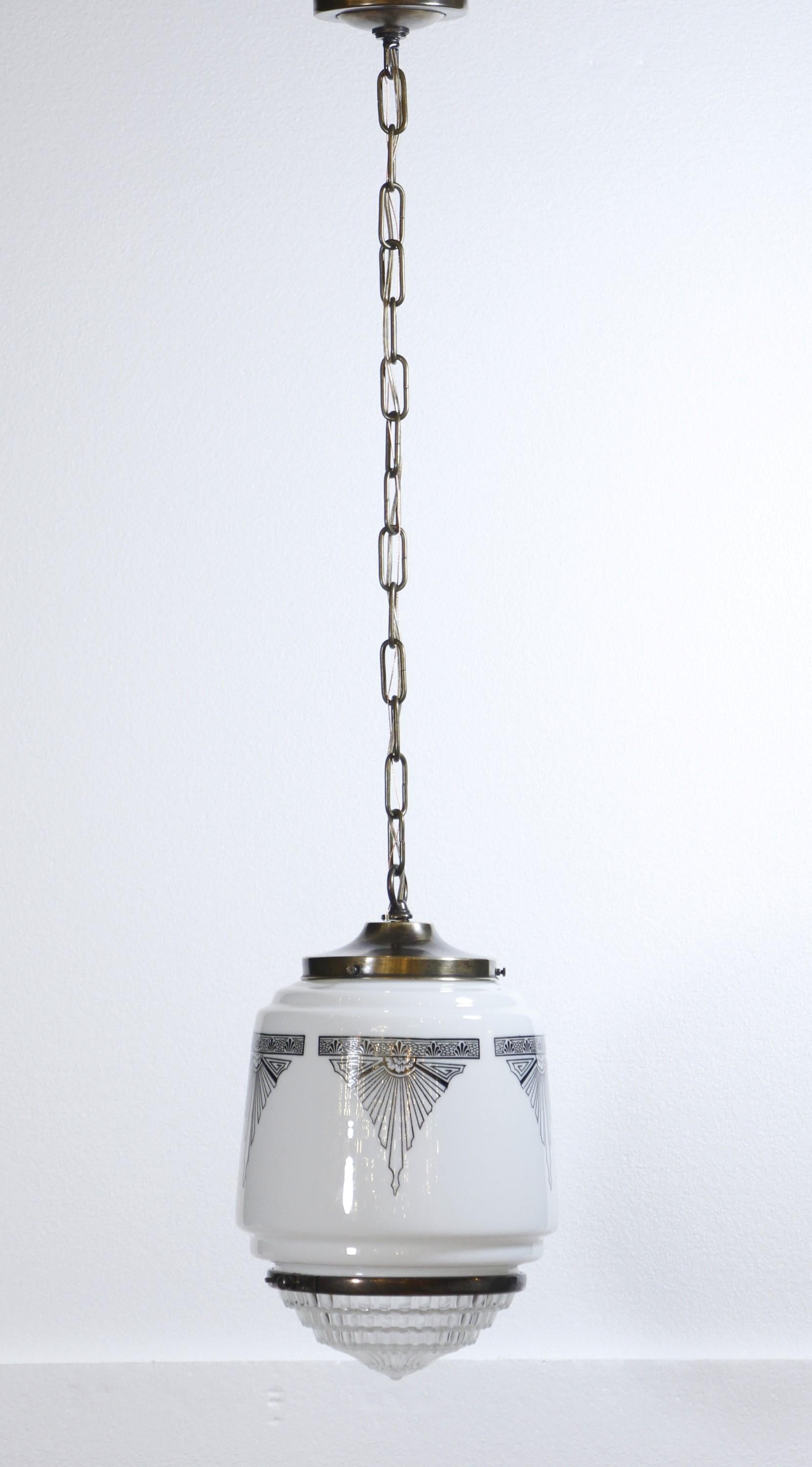 1930s old new stock Art Deco milk glass shade with newly wired pendant chain fitter. The shade has black Art Deco stenciling with a clear Fresnel lens at the bottom. The glass is old new stock and never used. Small quantity available at time of