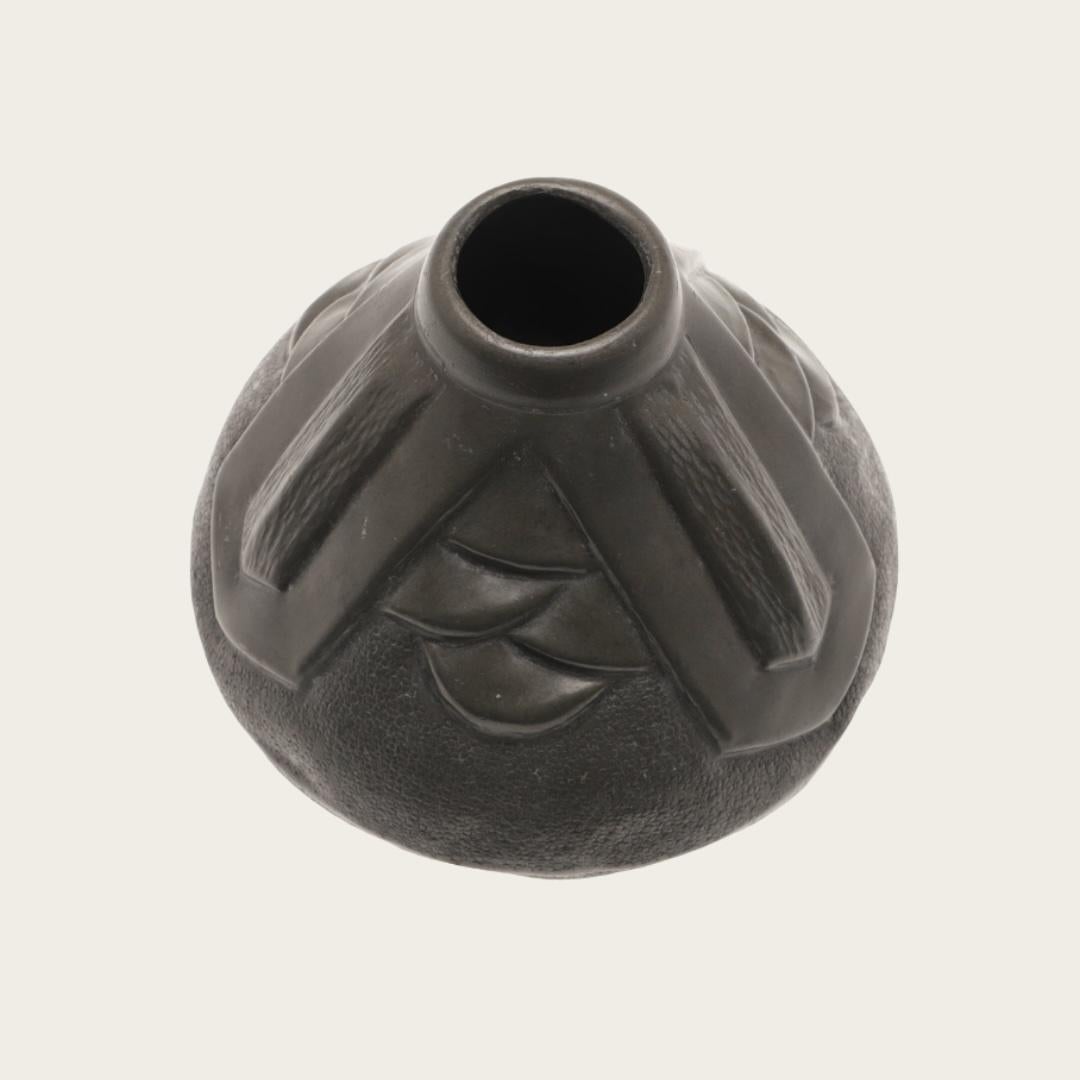 Datant des années 1930, ce vase présente un motif architectural Art déco stylisé. Il est signé d'un côté et porte des marques imprimées sur la base.