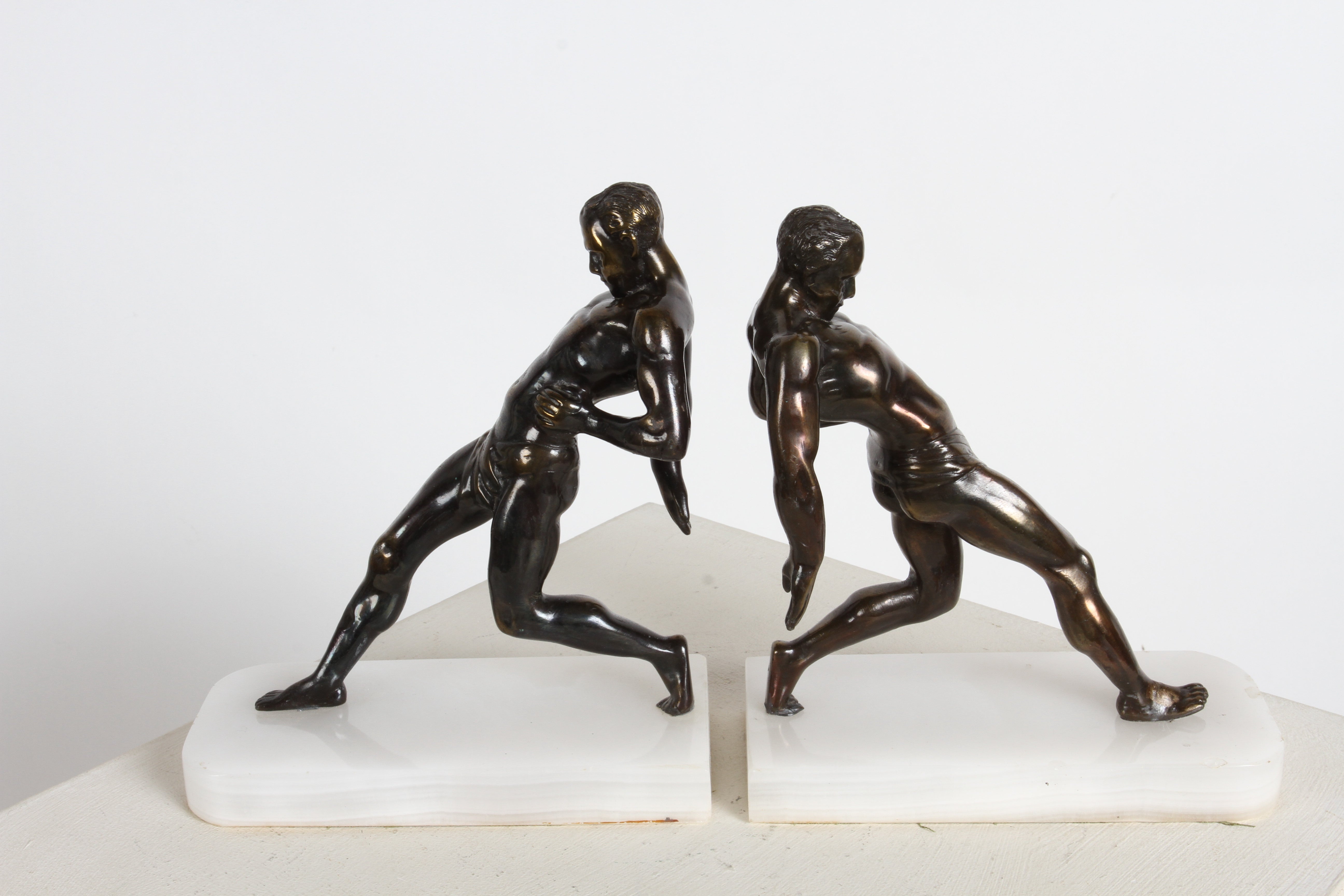 Pair of classical form Art Deco semi nude male athletic runner bookends on white alabaster bases. Attributed to artist  R. Vramant, France 1930s. Made of Spelter with bronze plating. Some minor chips to alabaster, see photo. 