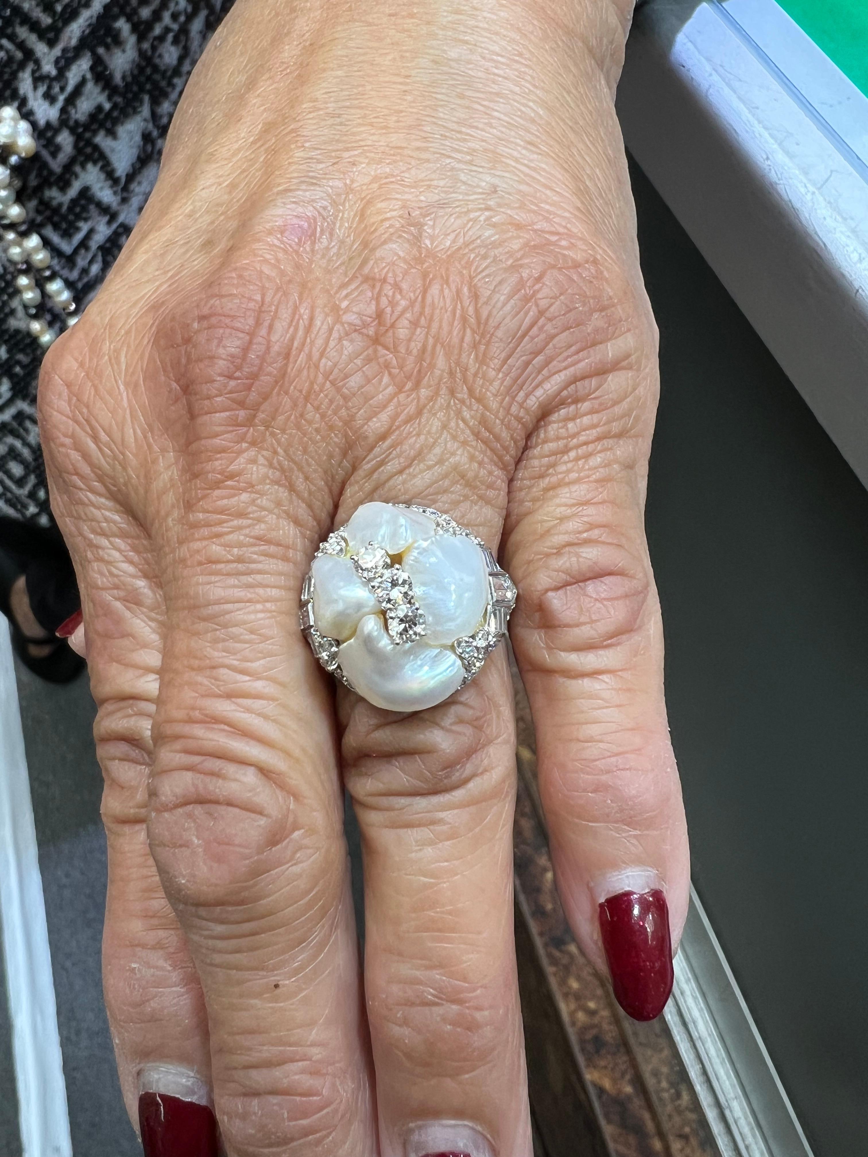 1930er Art Deco Flussperlen und Diamant Platin Cocktailring.

Der Art-Déco-Ring mit Flussperlen und Diamanten aus Platin aus den 1930er Jahren ist ein Beispiel für die charakteristischen Merkmale der Art-Déco-Epoche, einer Zeit, die durch eine