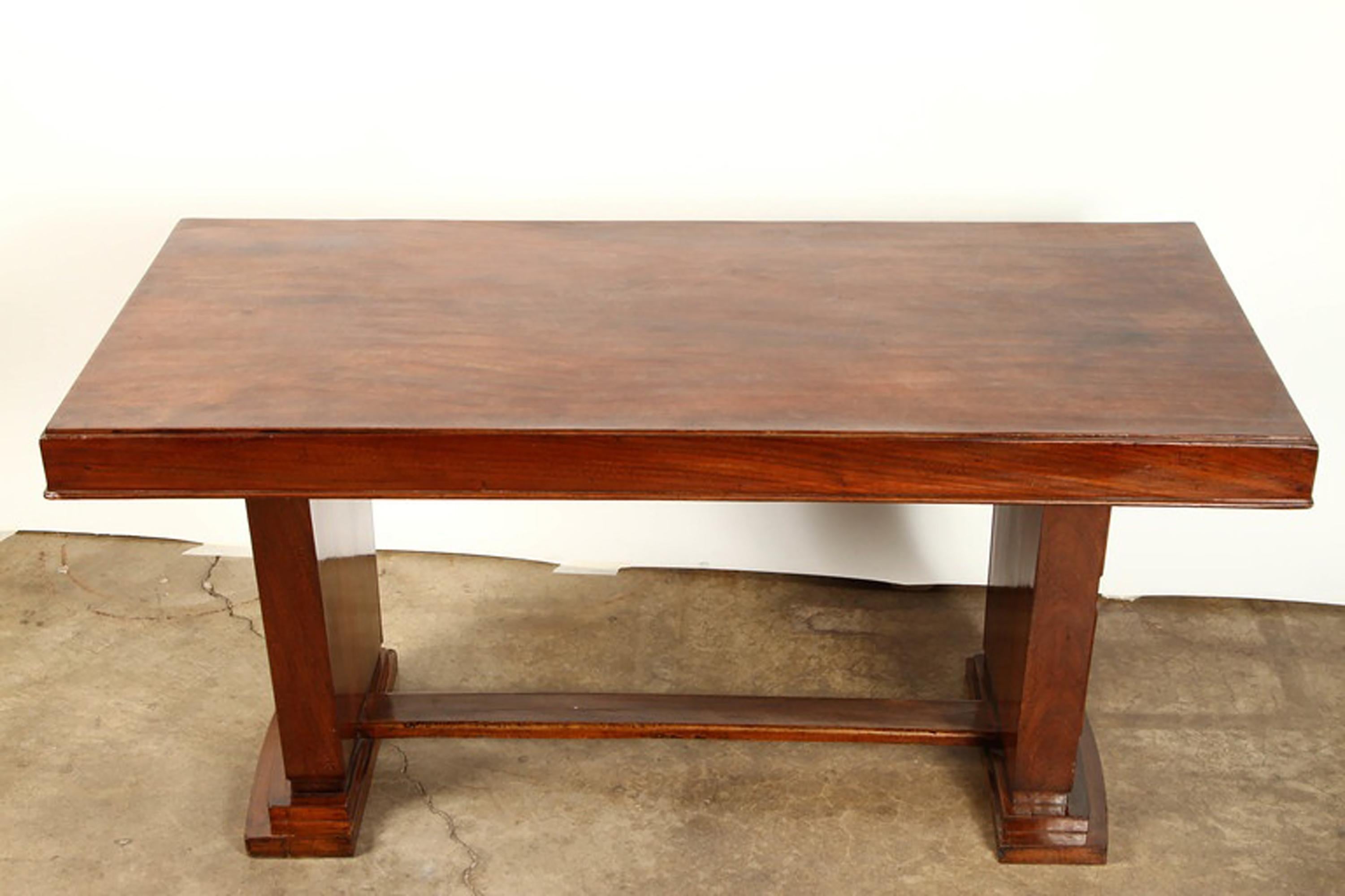 An Art Deco rosewood French Colonial desk, created circa 1930 for the expatriate market in Indo China. In richly colored and grained rosewood, with elegant lines. Simple moldings outline the edges of the top and the square panels of the slightly