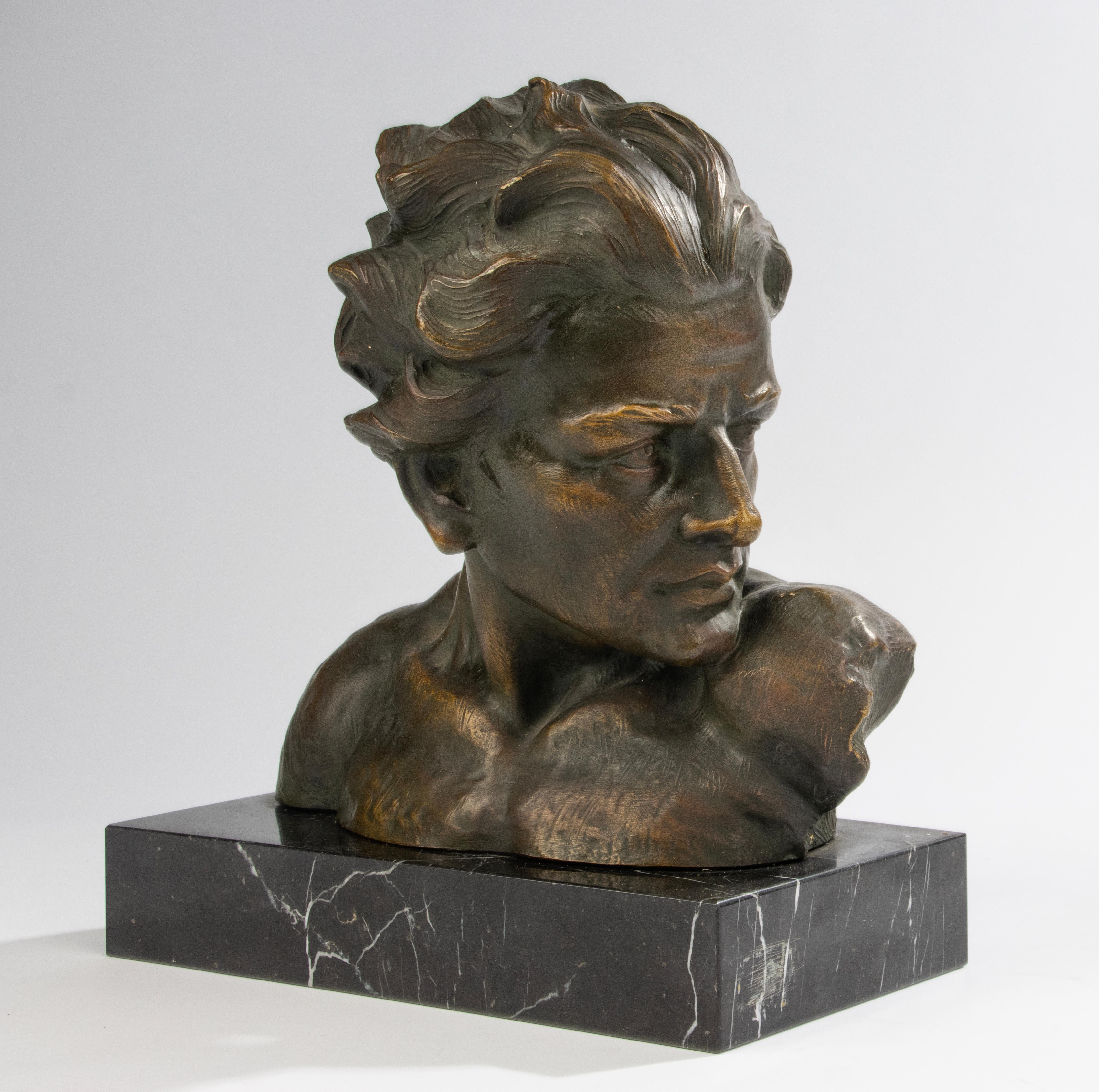 Preciosa estatua expresiva de la época Art Déco, busto de hombre joven, 'En Profil' La estatua es de terracota con base de mármol negro. La estatua está patinada en un color verde con bronce. En el reverso figura la firma del artista, Johannes