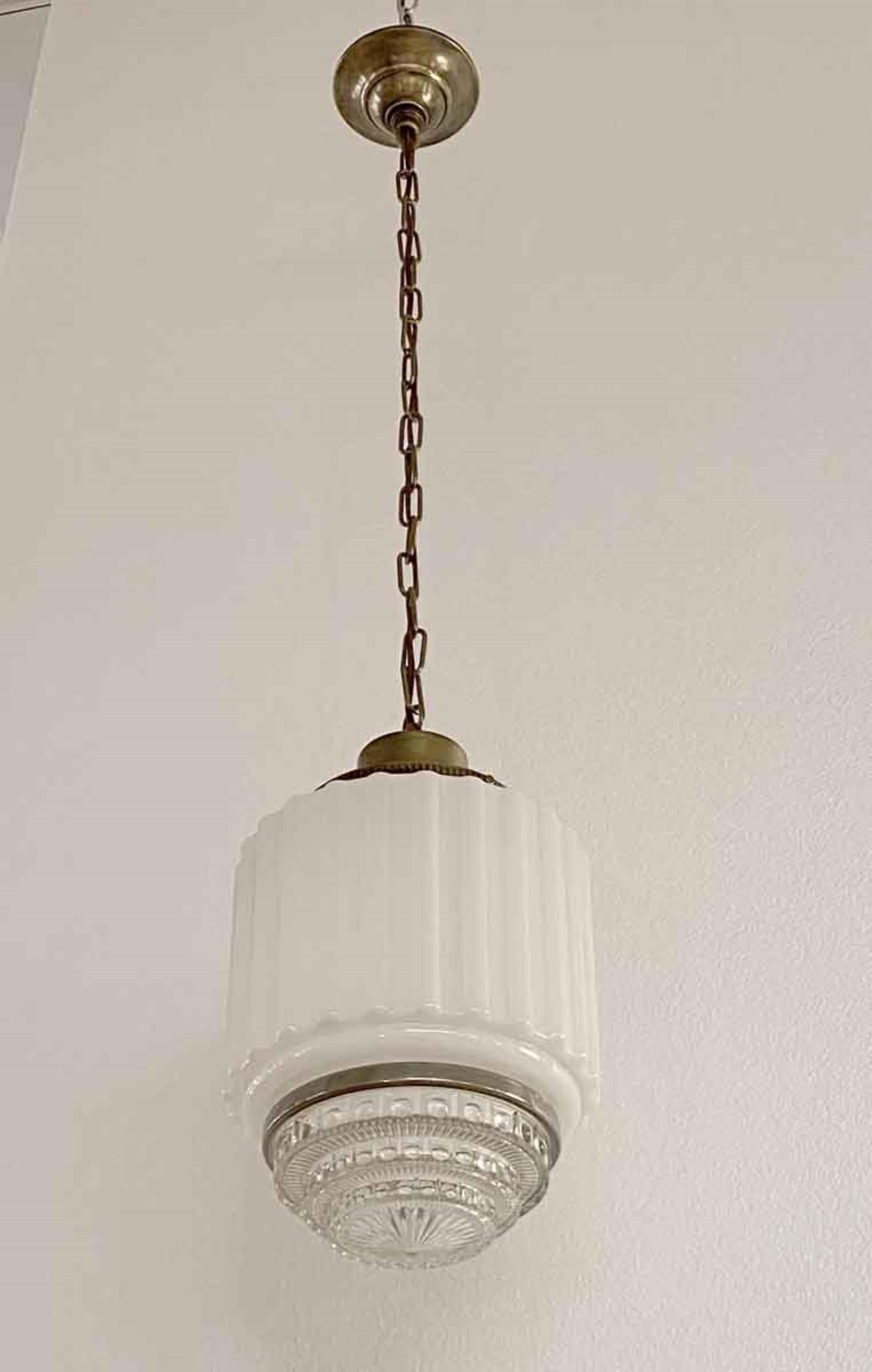 This is a 1930s Art Deco skyscraper pendant light. The globe consists of two parts. The top portion is translucent white fluted glass which diffuses light in the room. The bottom portion is made of ornate clear cast glass with a 3-tier step down.