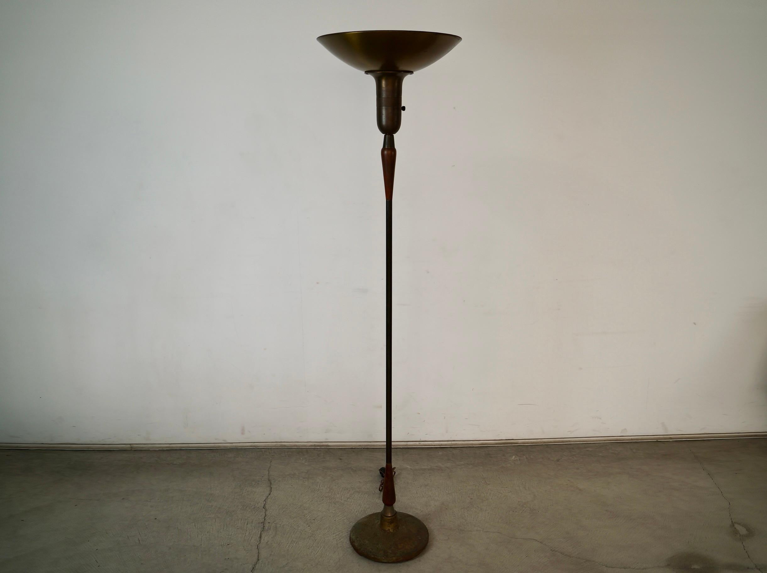 1930's Art Deco antique floor lamp for sale. It's a torchiere floor lamp that has been professionally re-wired. It's made of metal and solid brass, and has two solid walnut spindles with an aluminum place for the torch shade. It has the original