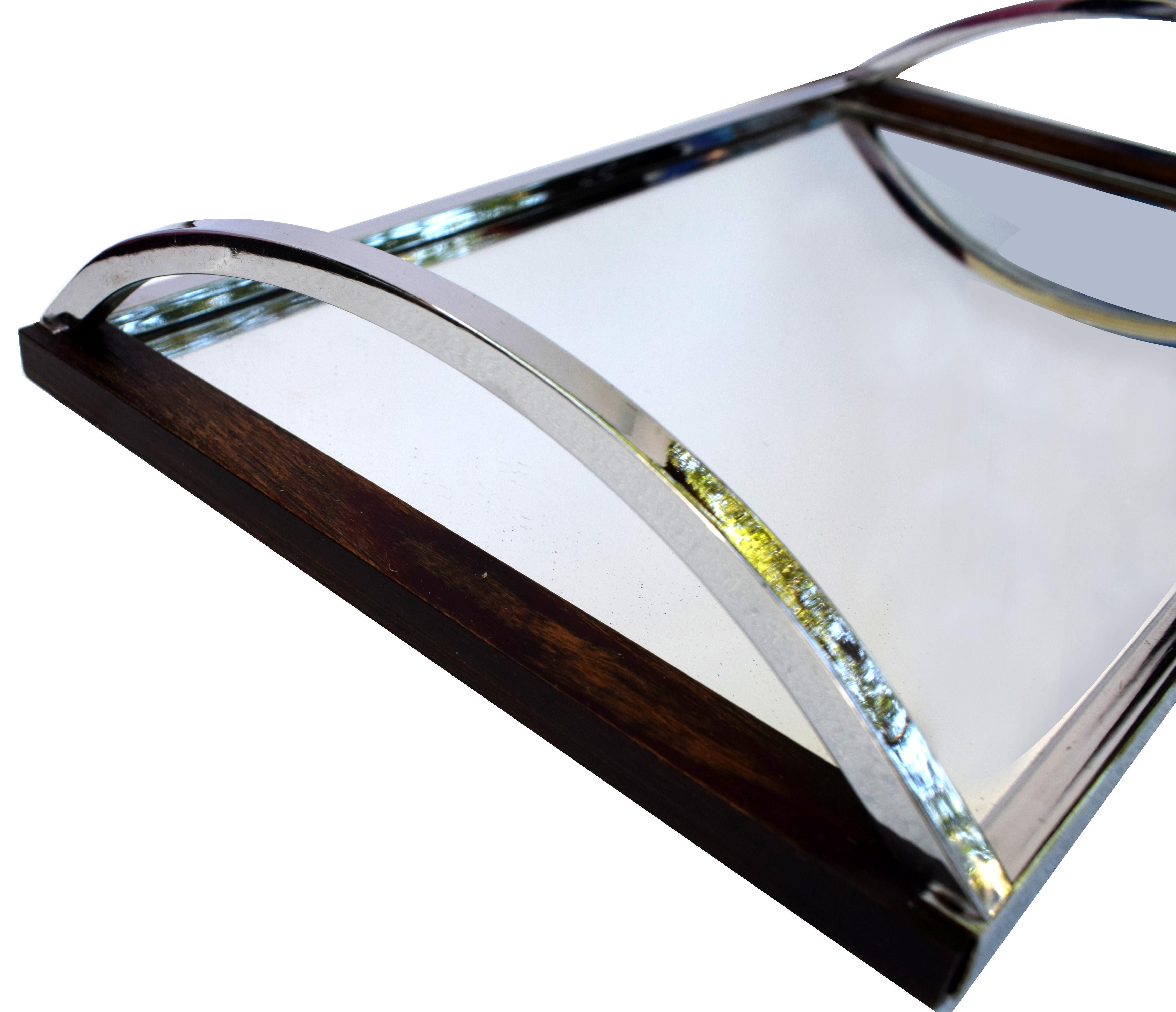 1930s Art Deco tray with a fully chromed frame with walnut accent trim. Arching chrome handles support the all mirror base. In great condition for a utility piece and something special to add that extra glam to serving drinks. These trays are ideal