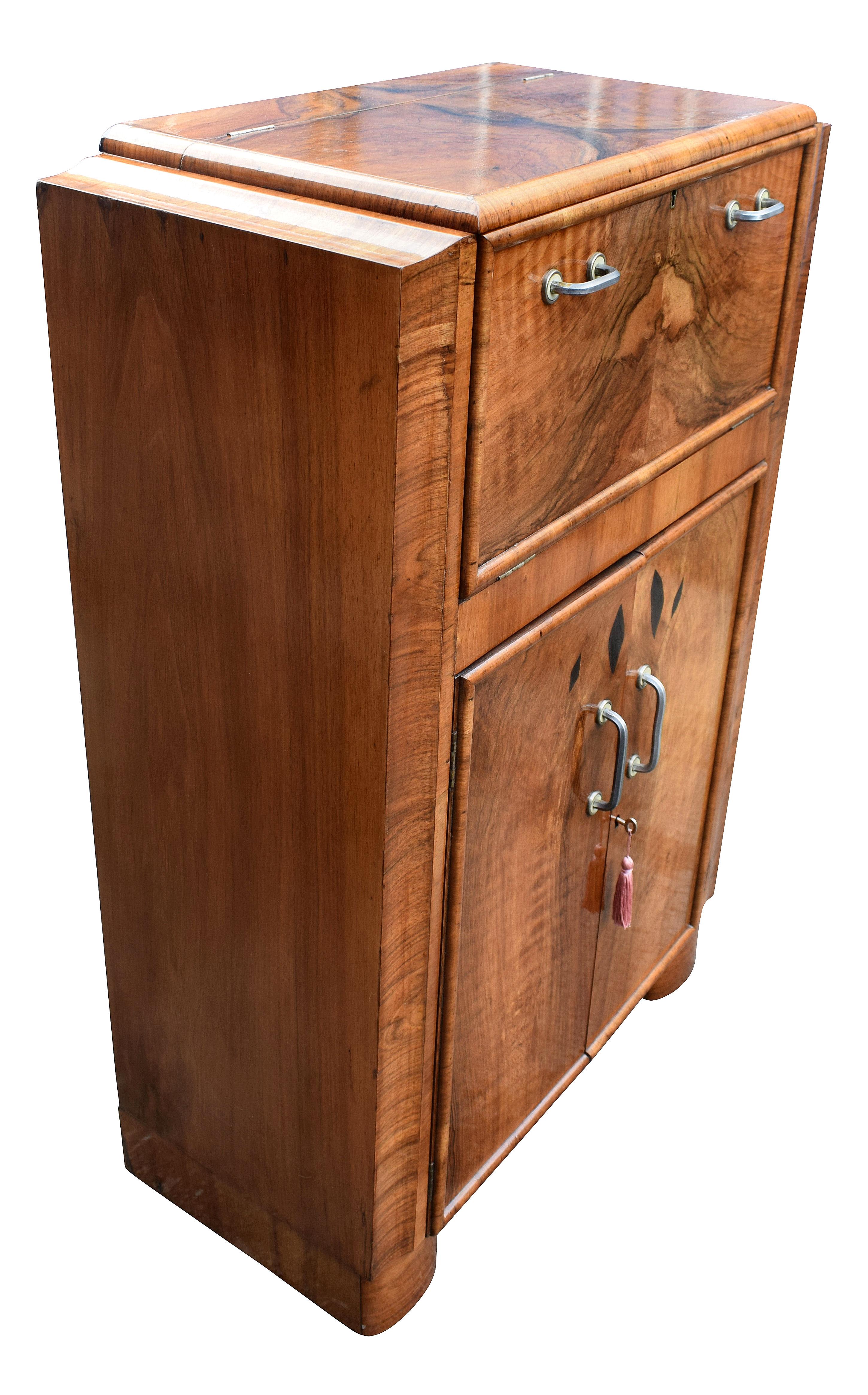 Beautiful 1930s Art Deco walnut upright cocktail cabinet, every Deco interior should have one of these ! Features a drop down top which reveals a mirrored interior and storage for bottles and glasses. A generously sized cupboard below offers plenty
