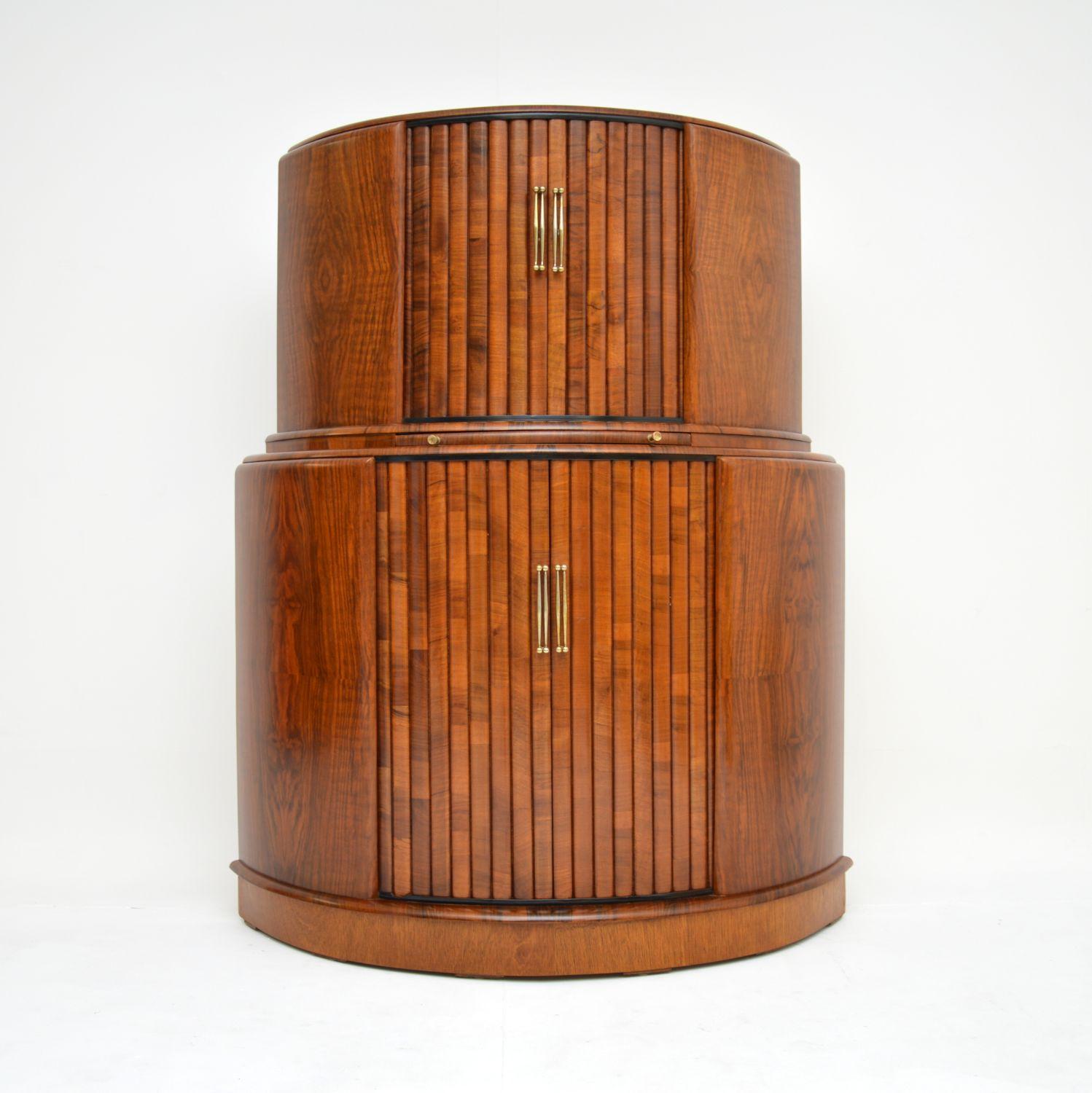 A stylish and very well made Art Deco cocktail drinks cabinet in Walnut. This was made in England, it dates from around the 1930-50’s.

The quality is excellent, this has clever tambour rolling doors at the top and bottom section. The top section