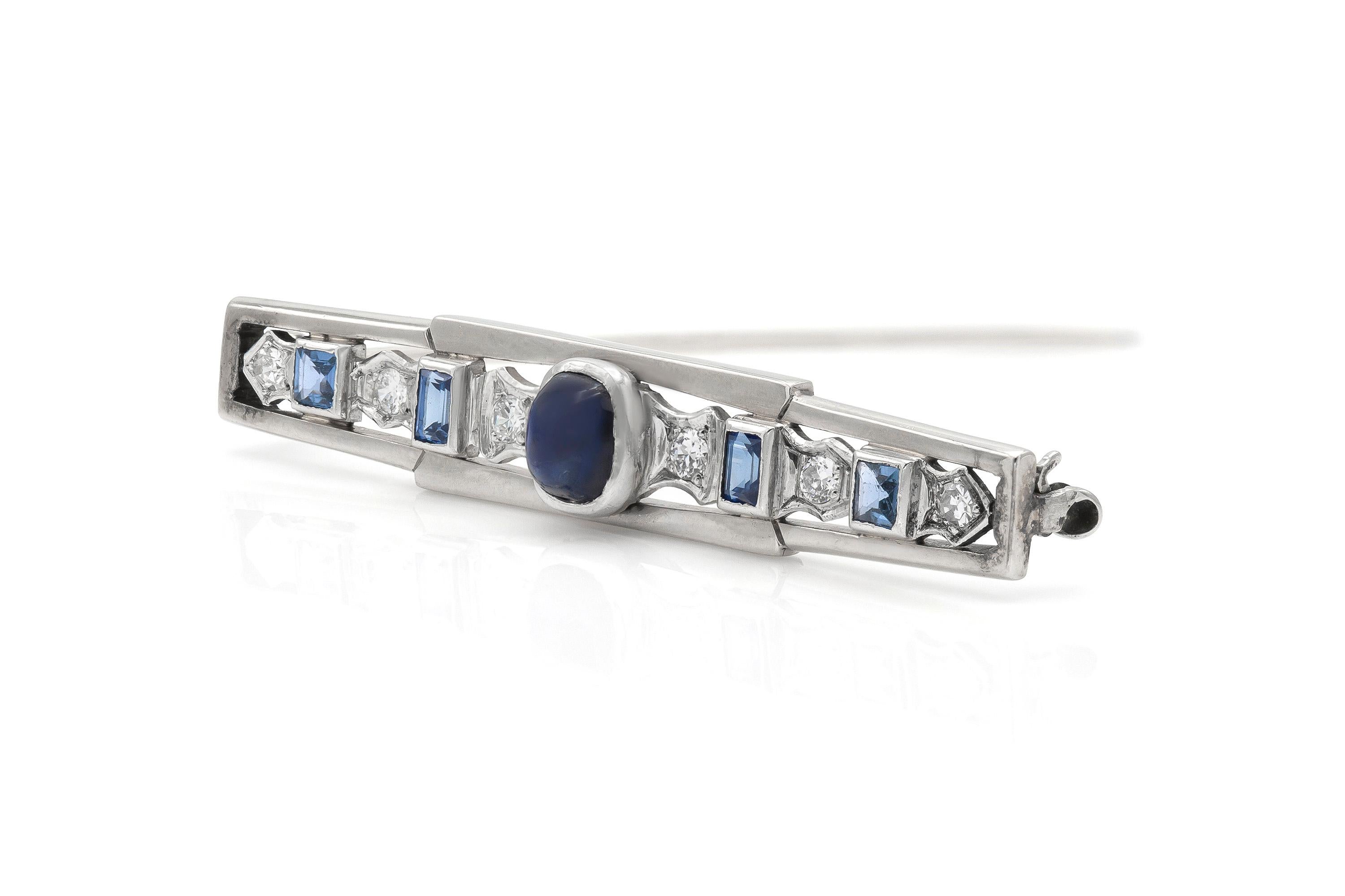 Finely crafted in 15k and 10k white gold with a center Cabochon Sapphire weighing approximately 1.00 carat. The pin features squre and rectangle cut Sapphires weighing approximately a total of 0.60 carats and Diamonds weighing approximately a total