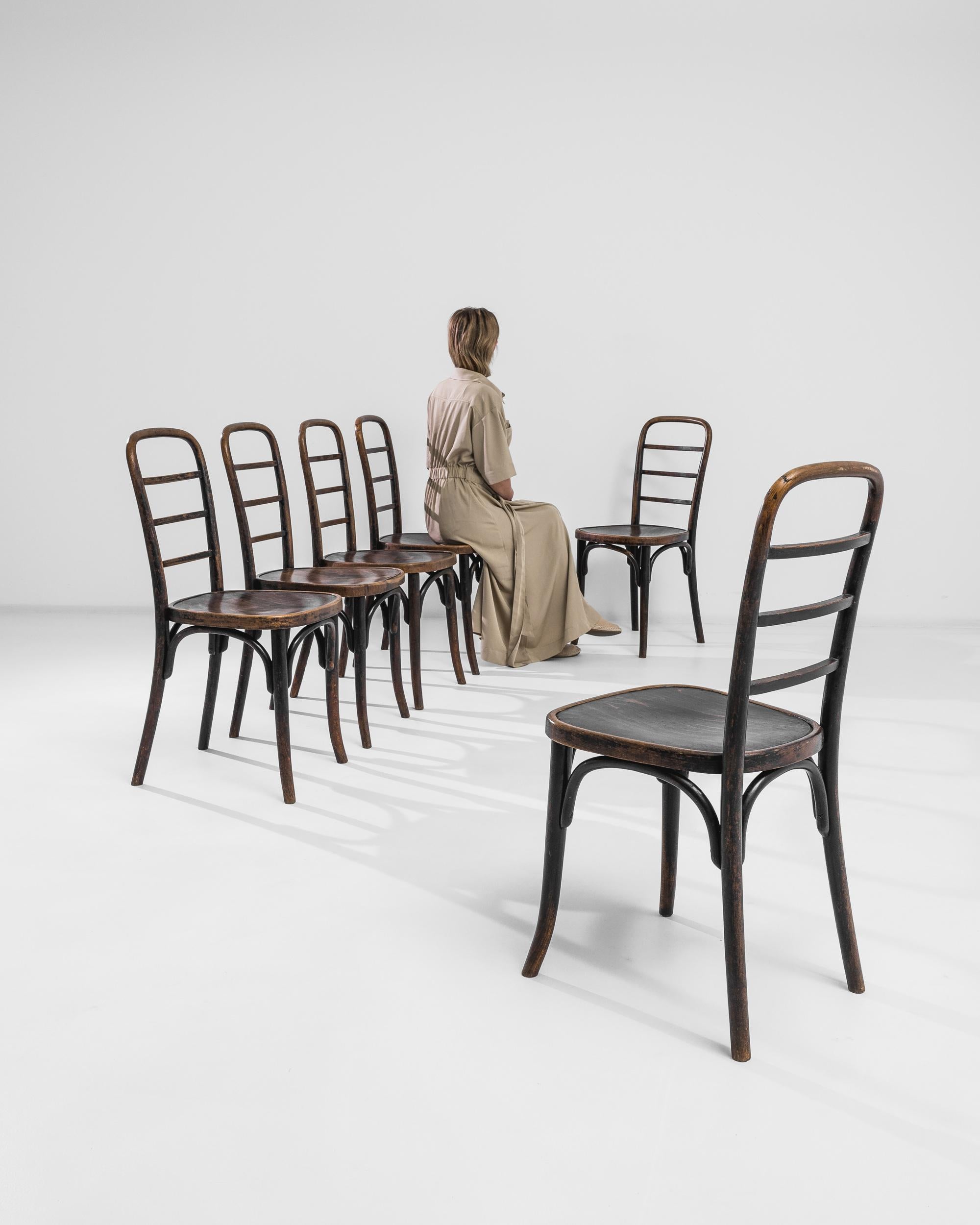 A set of six Thonet dining chairs produced in Austria circa 1930. Standing firmly on their slender wood bent legs, these stylish chairs feature comfortable wide seats and elongated ladder backrests with smoothly rounded tops. The deep tone of the