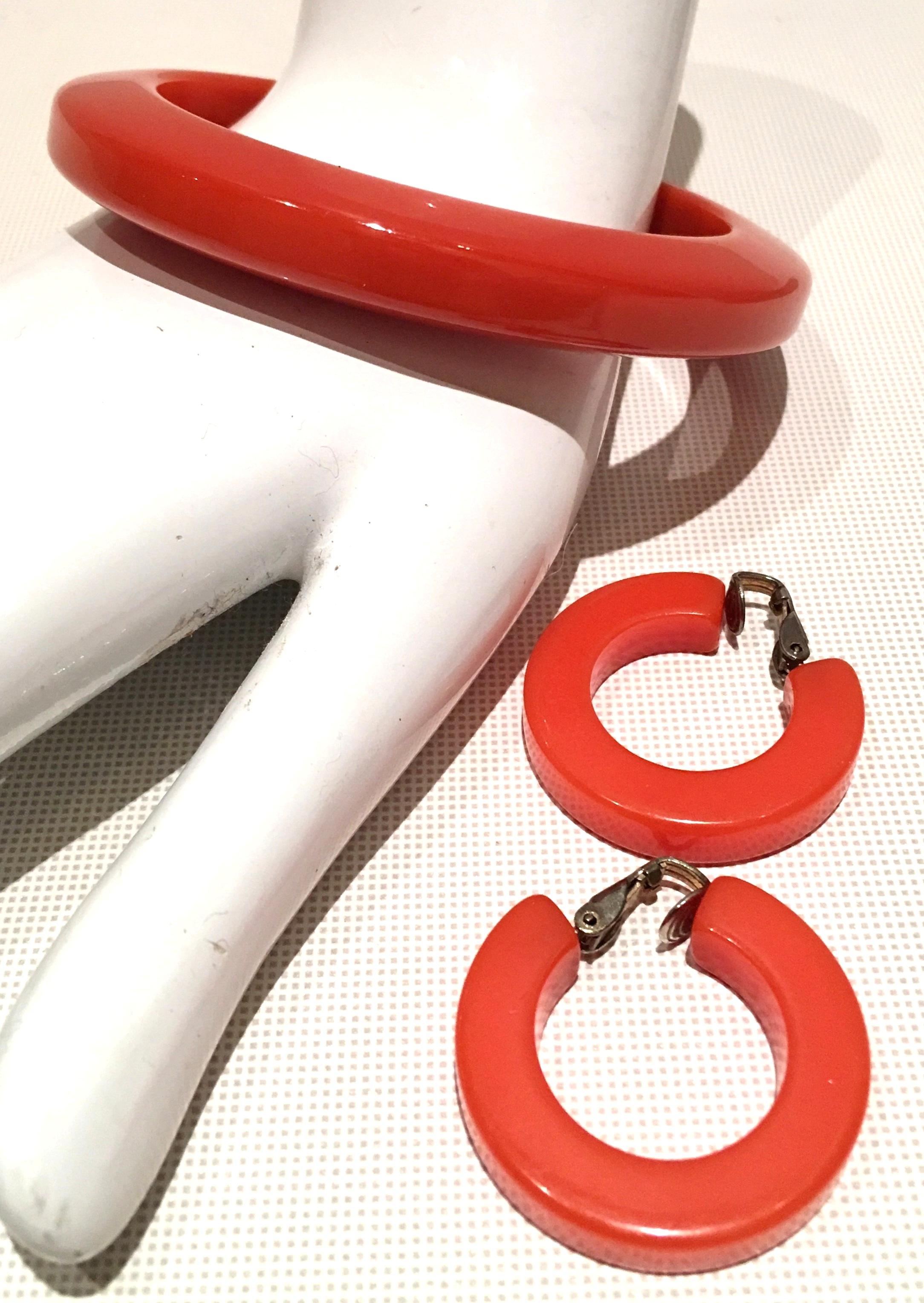1930'S Art Deco orange Bakelite bangle bracelet and hoop earrings set. Earrings are tubular and clip style with sterling silver detail. The bangle is tubular with rounded edges and has an interior diameter of, 2.5