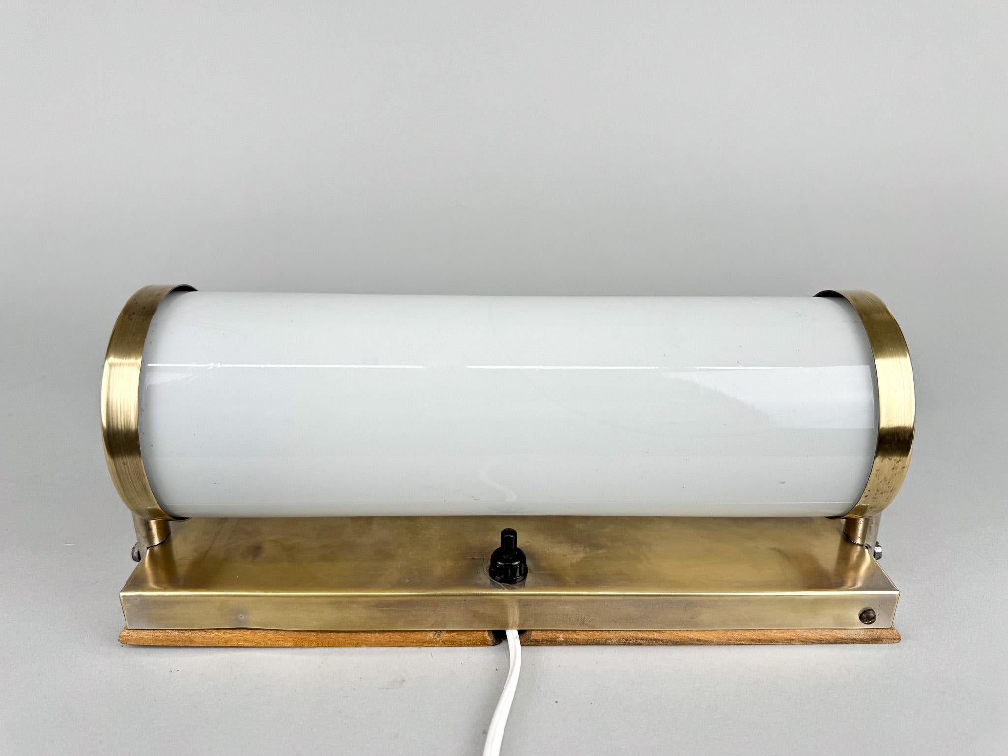 Bauhaus tubular wall light made of brass and milk glass. Produced in former Czechoslovakia in the 1930's. 
The switch on the lamp is not functional. The lamp is rewired with a new switch on the cable. 
Bulb: 1 x E14. US adapter included.