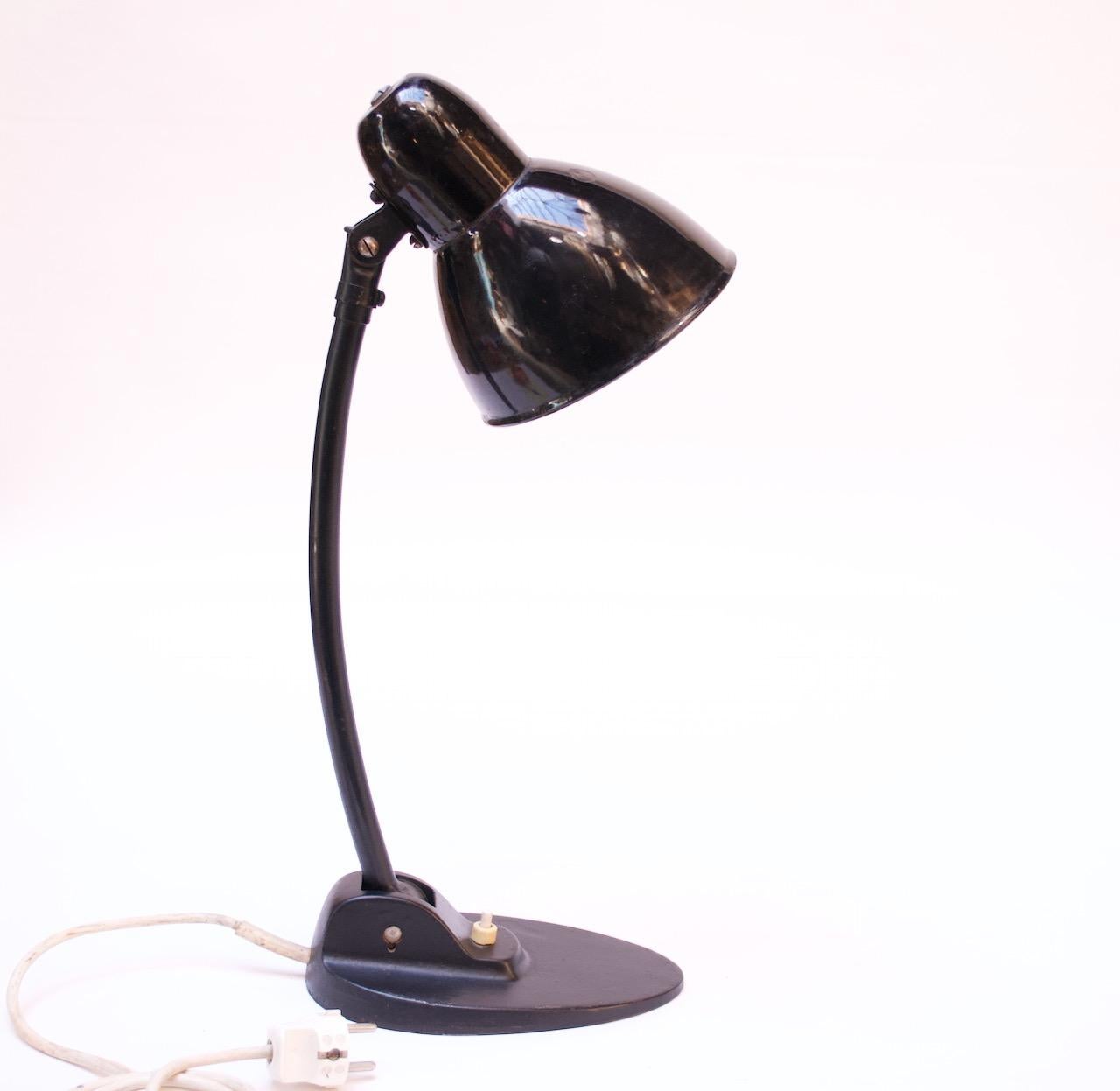 Desk / table lamp by Jacobus of Germany featuring a porcelain enamel shade and painted metal base / stepped foot, circa 1930. Highly functional with an articulated stem and fully adjustable shade.
Original paint shows heavy wear (dents, scratches,
