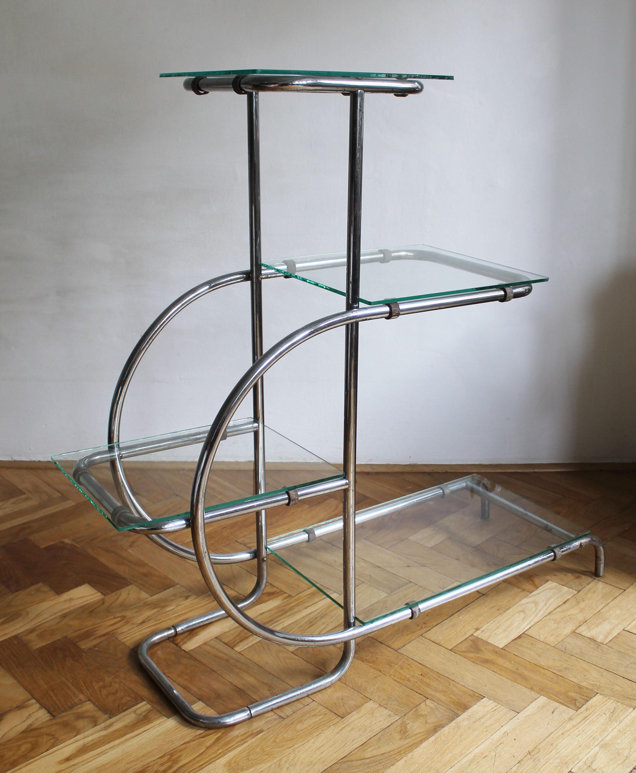 A modernist flower stand made up of four glass shelves of different sizes, positioned at different heights and with a continuous tubular frame.  Designed to display plants and flowers in a beautiful composition.

This piece is a prime example of the