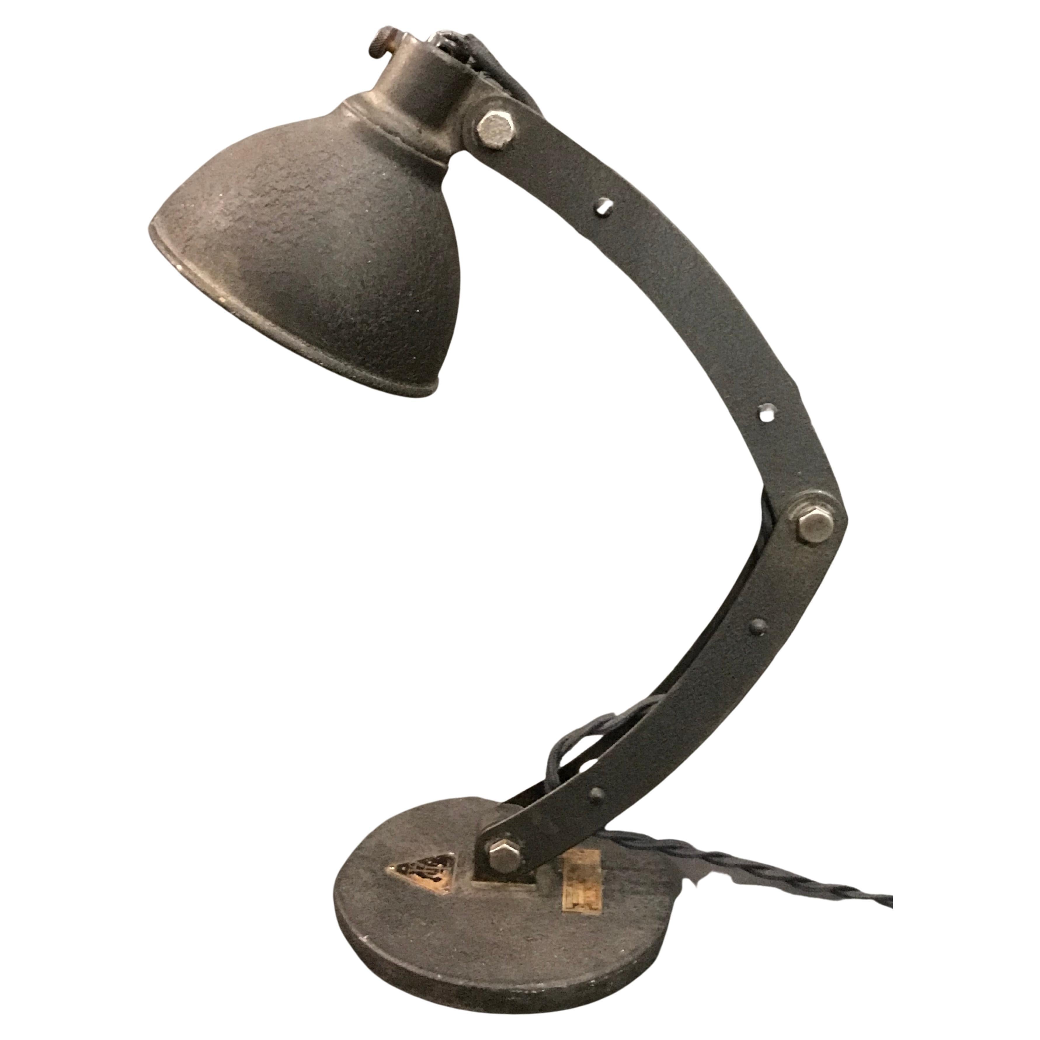 A rare 1931 Bausch and Lomb articulating task lamp in textured black steel with original and irreplaceable high intensity medical grade reflector marked with the B&L Logo from the era. The minimal frame with three points of motion is set over a