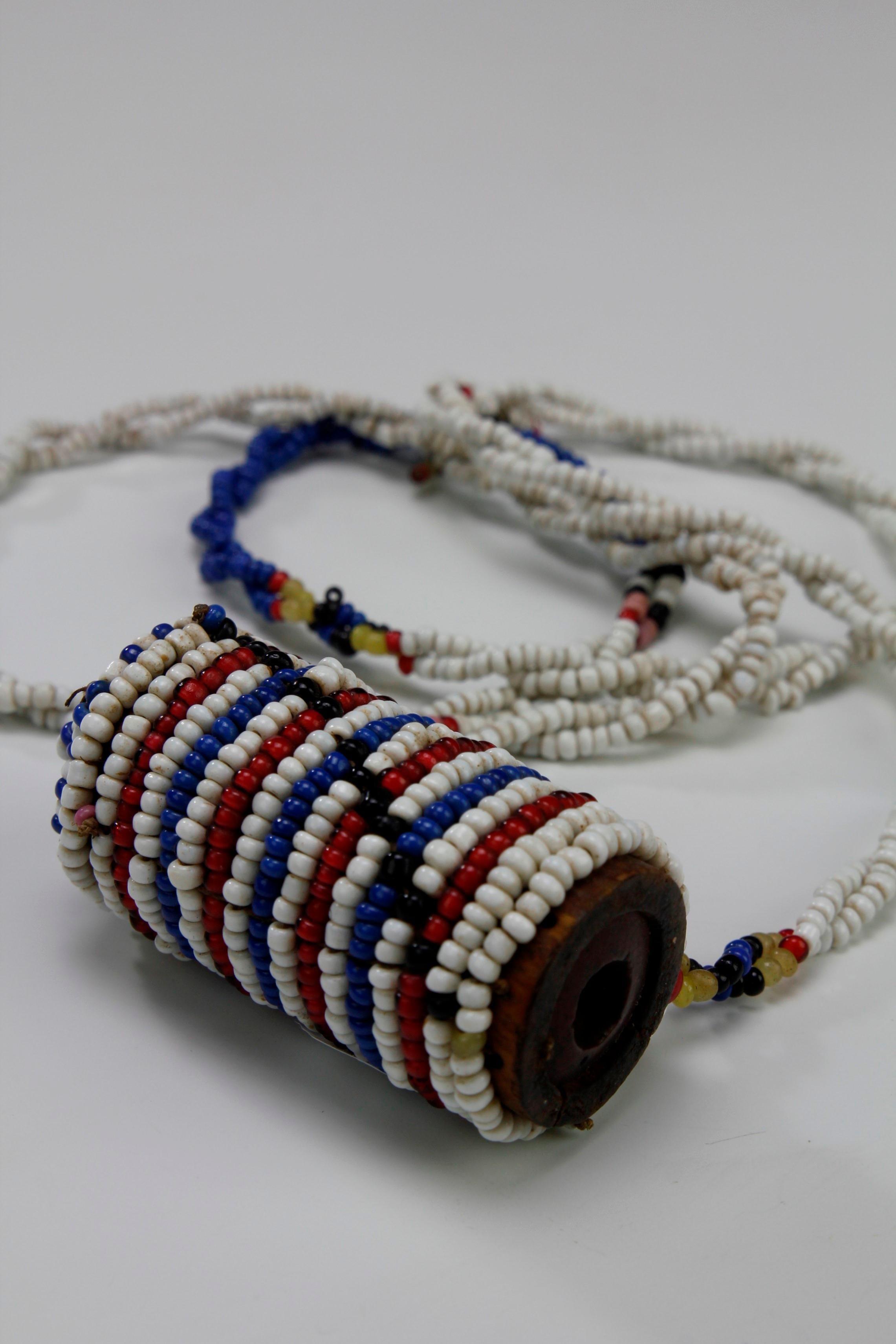 Dieser kleine Zulu's Schnupftabakbehälter aus den 1930er Jahren ist wunderschön mit Glasperlen verziert. Auf der einen Seite befindet sich eine runde Öffnung, auf der anderen Seite kontrastieren sich überlappende blau-weiße Perlenstränge mit den