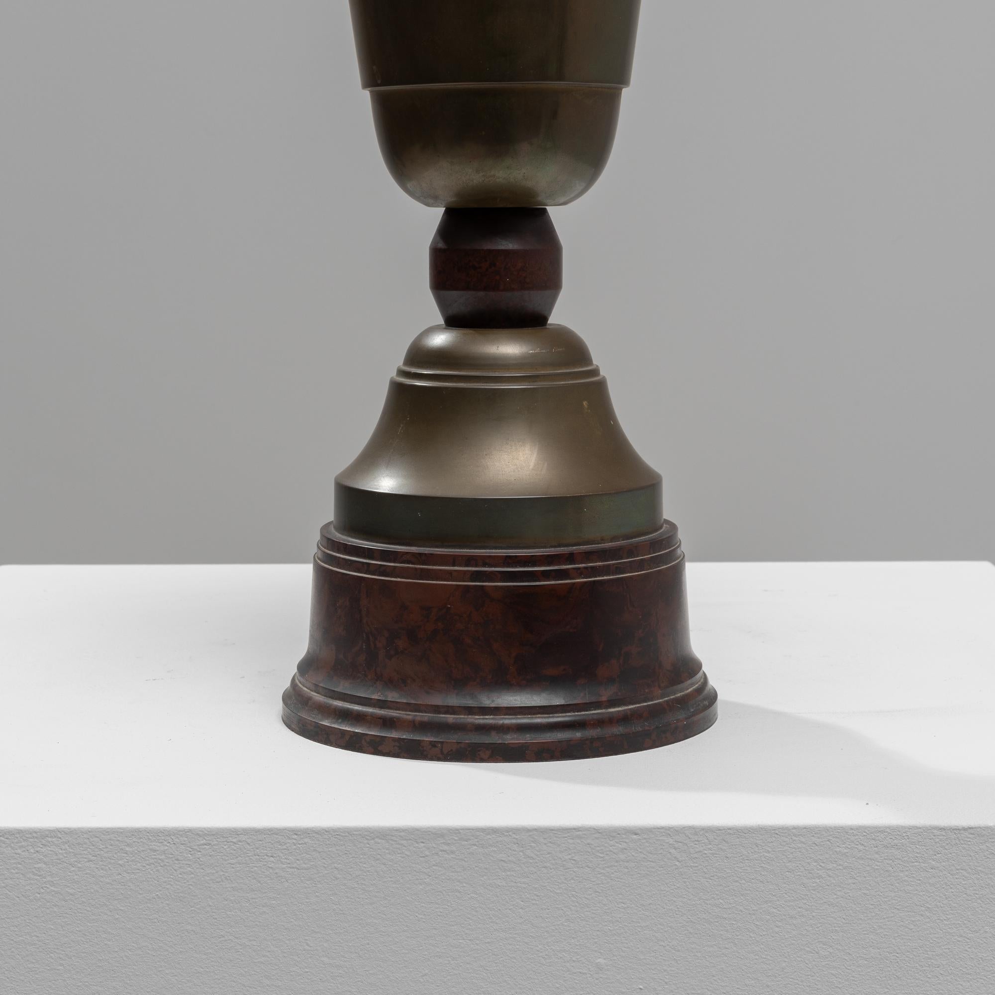 This 1930s Belgian brass goblet with lid is a splendid example of vintage elegance and intricate design. Crafted from high-quality brass, this goblet features a classic silhouette with a graceful stem and a sturdy, rounded base that provides