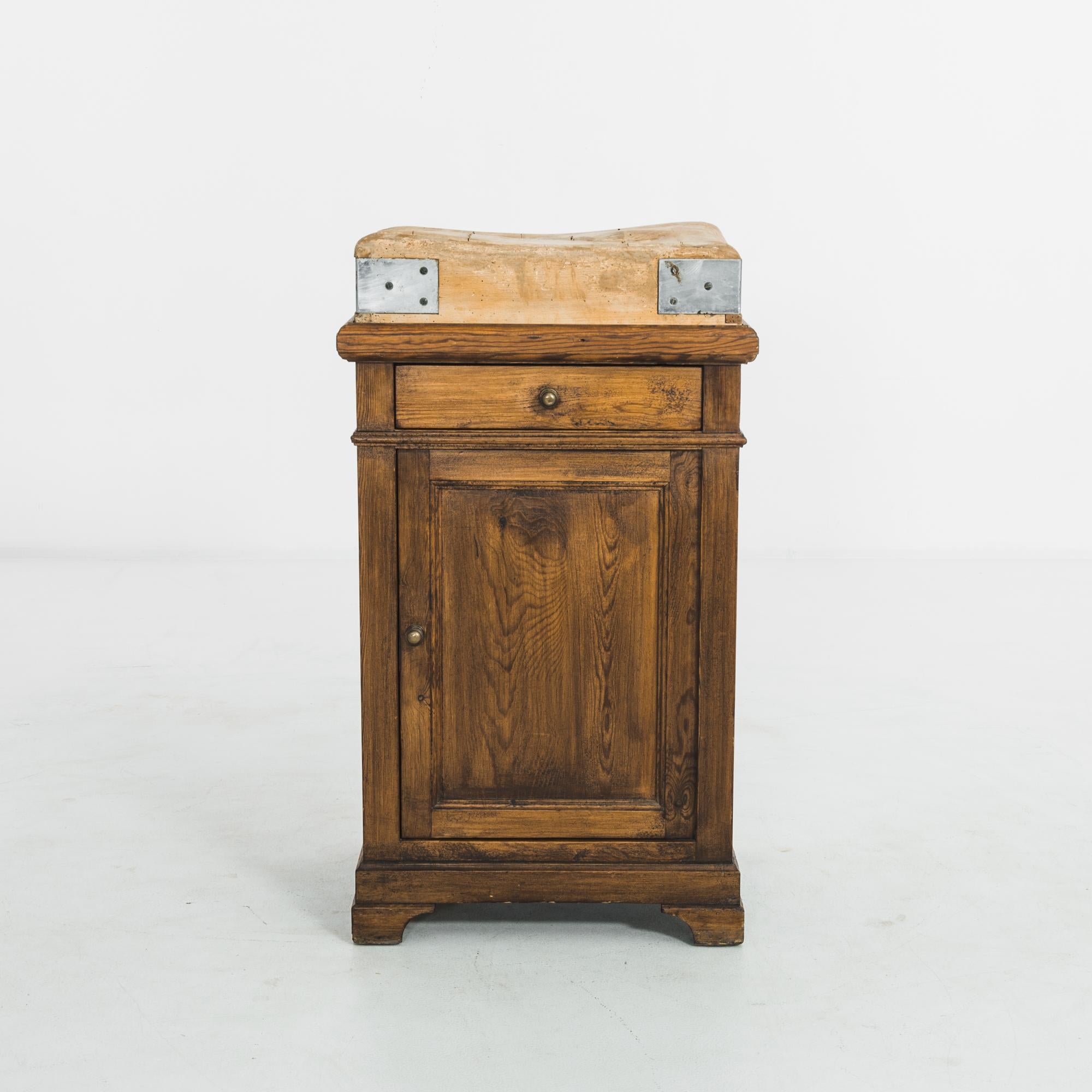 This wooden worktable was made in Belgium, circa 1930. Elevated on bracket feet, the rectangular table houses a drawer and a compartment with two shelves. It features round pulls and a smooth patina highlighting the curves of the wood grain. The top