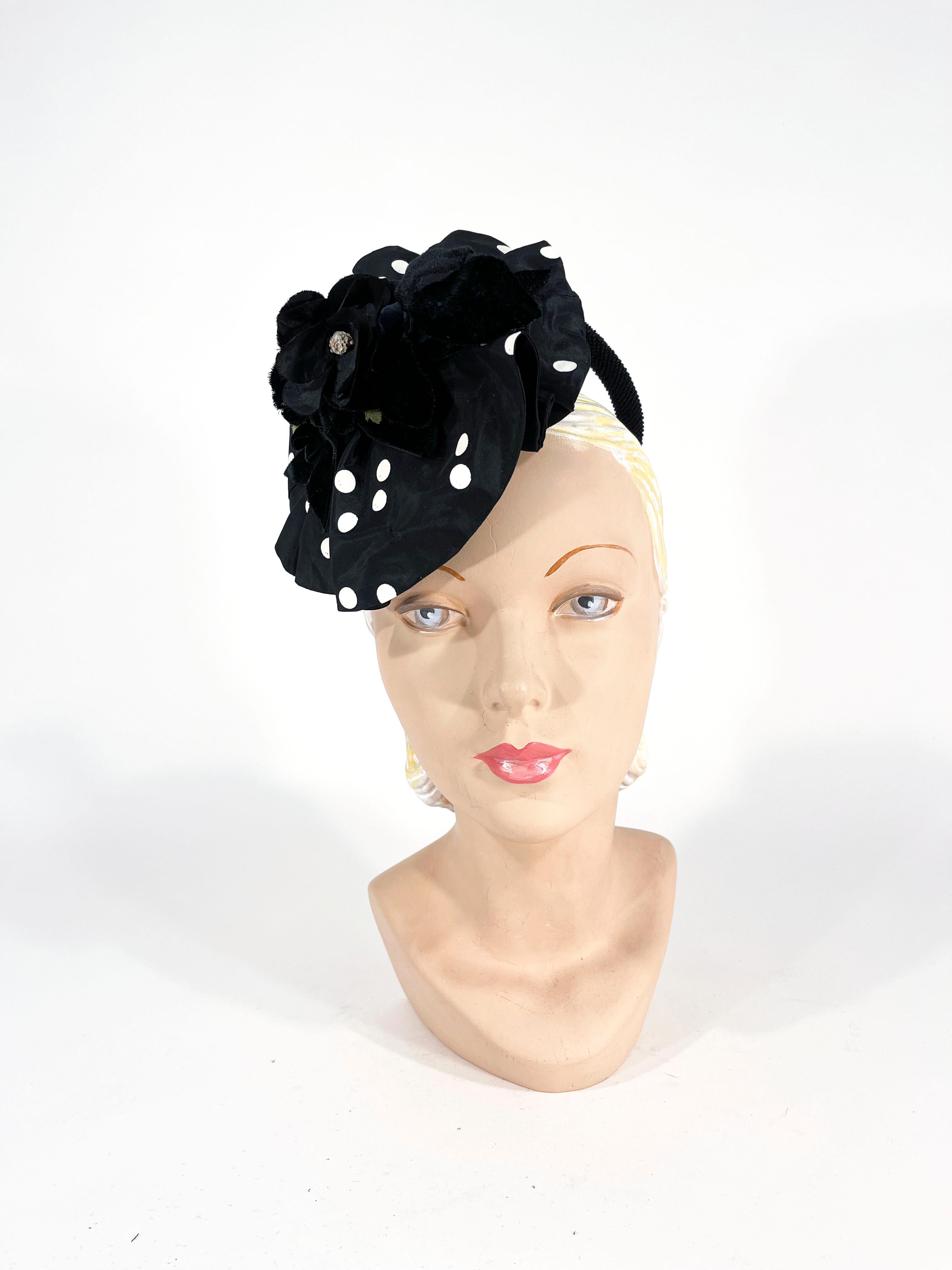 chapeau de cocktail des années 1930 en taffetas noir et blanc à pois avec un anneau de maintien structuré qui perche le chapeau sur le côté de la tête. Le tissu est froncé pour créer un grand volant et est surmonté d'une fleur en soie et velours et