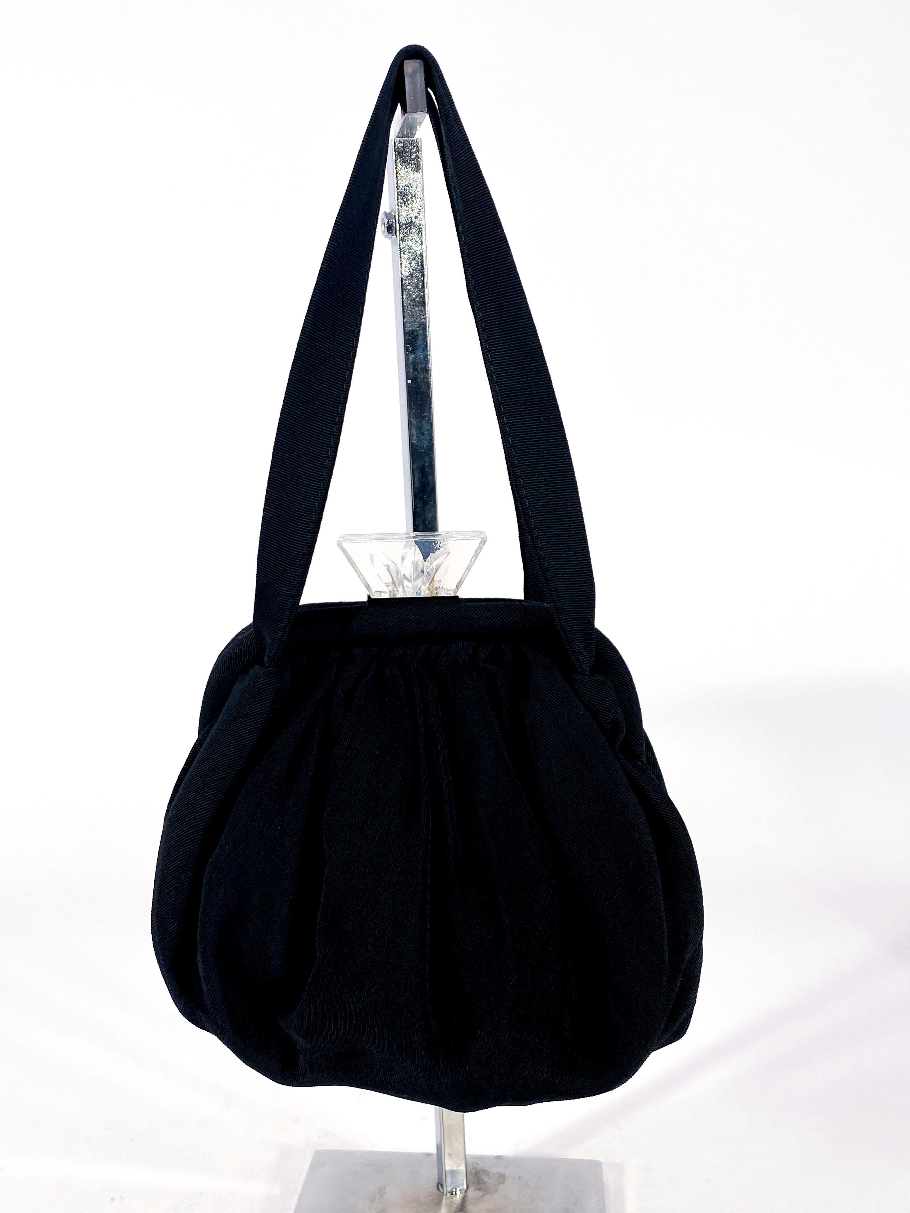 schwarze Abendhandtasche aus Twill aus den 1930er Jahren mit geschnitztem Art-Déco-Verschluss aus Lucit und Zuglasche. Das Innere des Portemonnaies ist mit schwarzem Twill gefüttert und hat ein integriertes Münzfach. Die gesamte Tasche ist mit einem