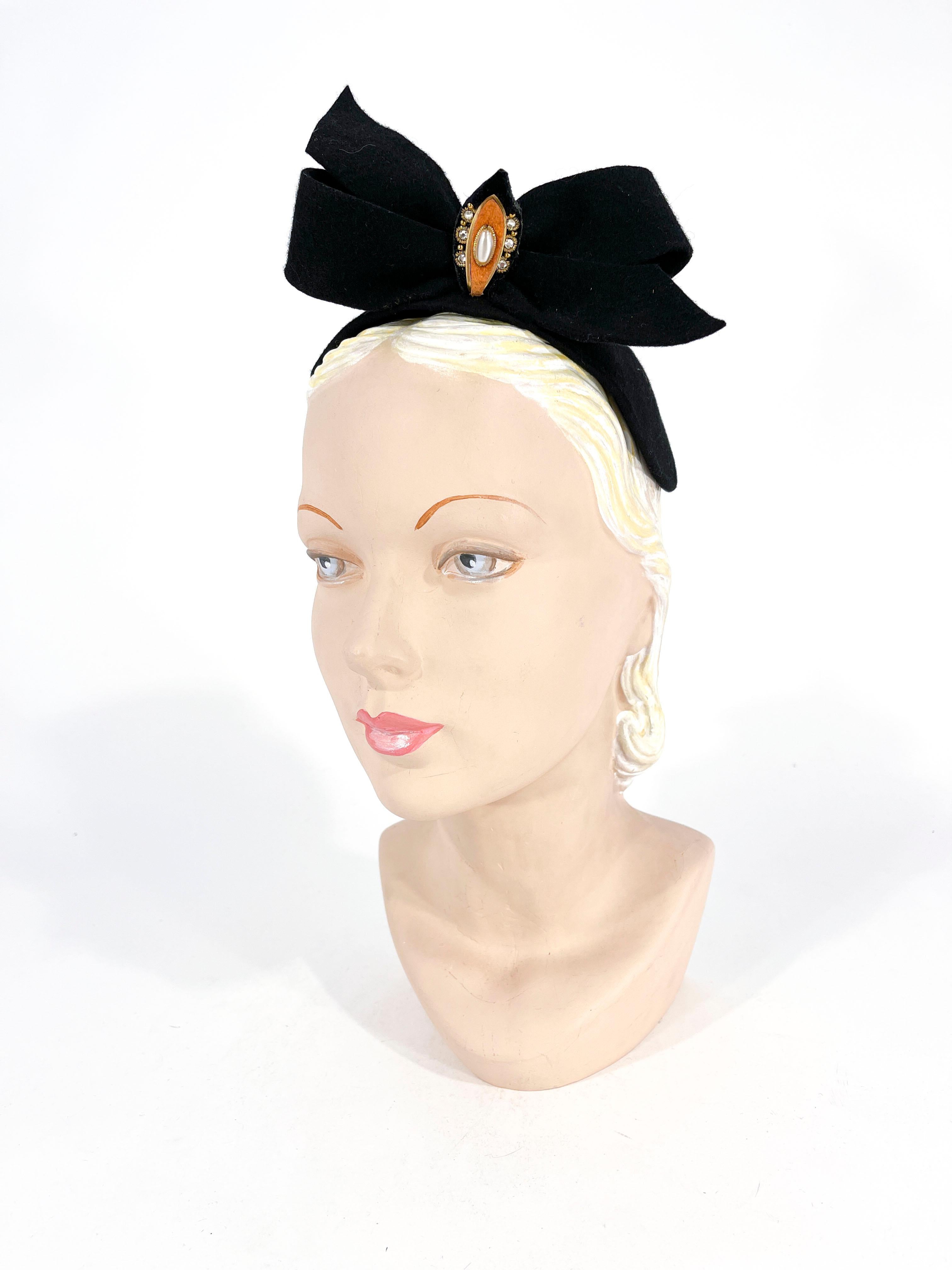 1930s Hand-sculpted beaver fur felt cocktail hat in the silhouette of the skull cap. It is decorated with an enlarged bow and decorated with a rhinestone, pearl, brass and felt accent. The interior of the hat is unlined and the frame of the hat is